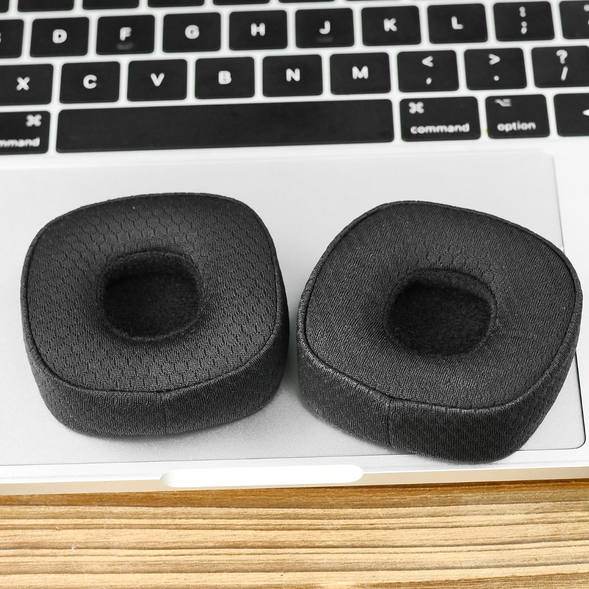 Due cuscinetti auricolari neri poggiano sulla tastiera di un computer.