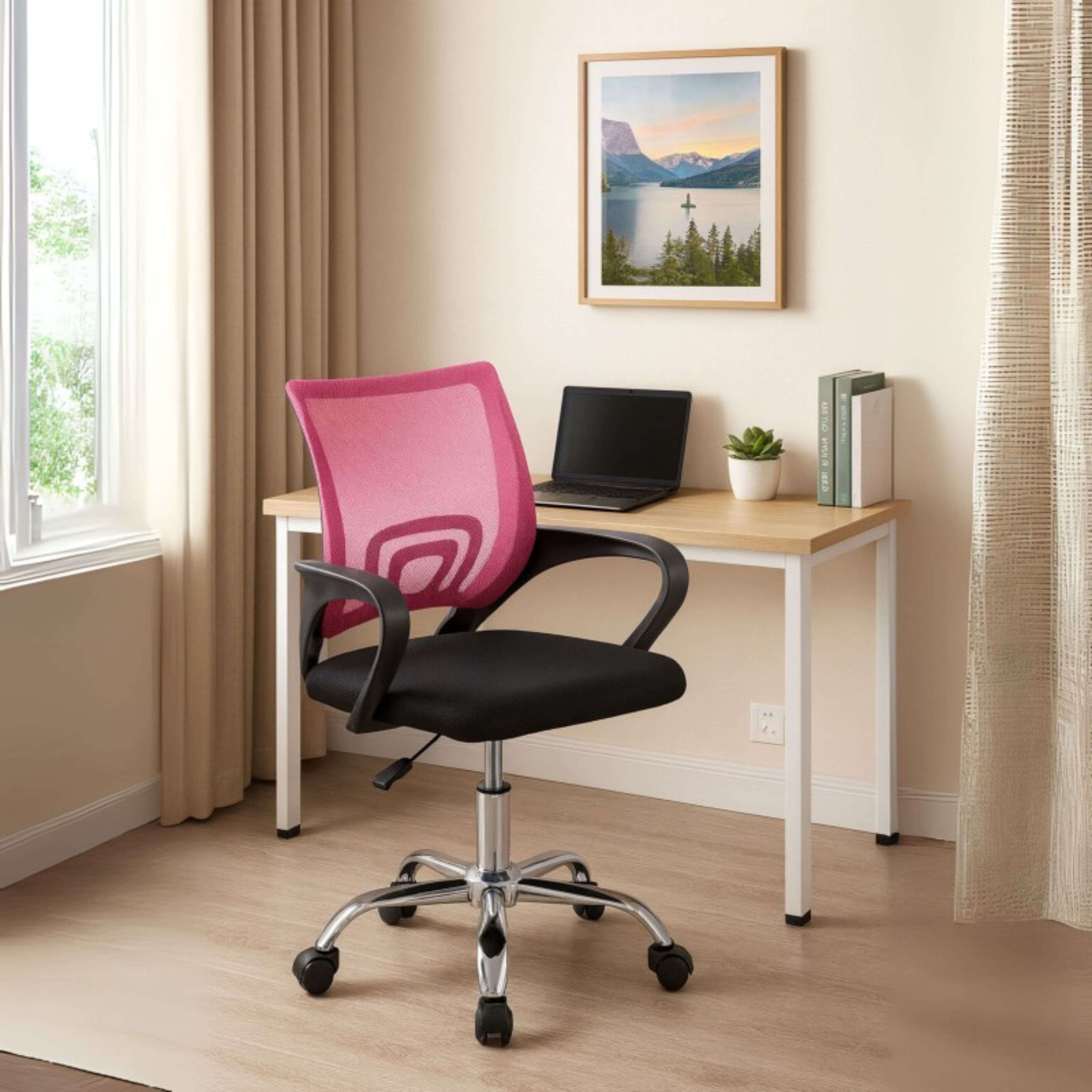 Una silla de malla rosa está delante de un escritorio con portátil y libros.