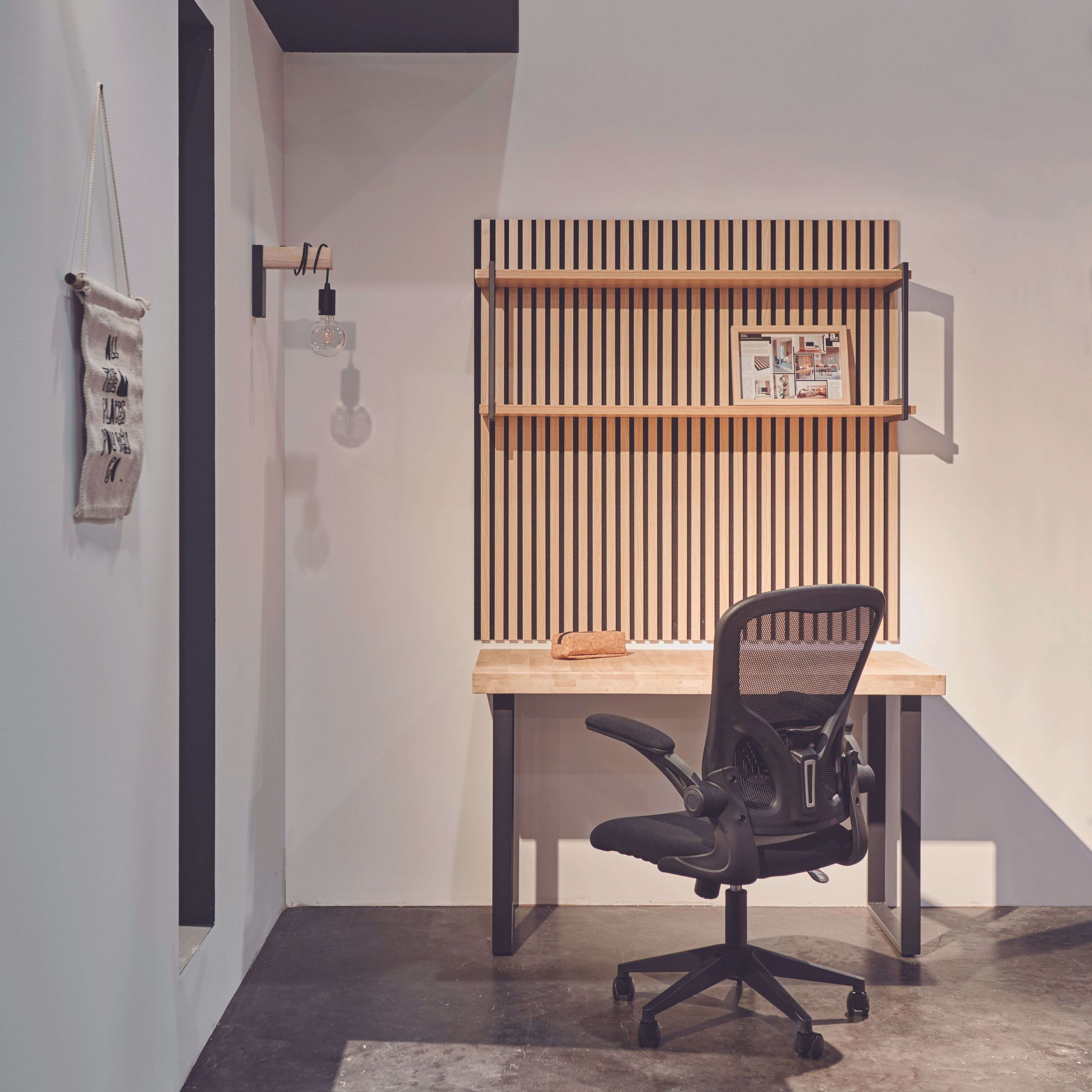 Un escritorio con una silla de oficina delante. Un estante con pared de listones detrás.