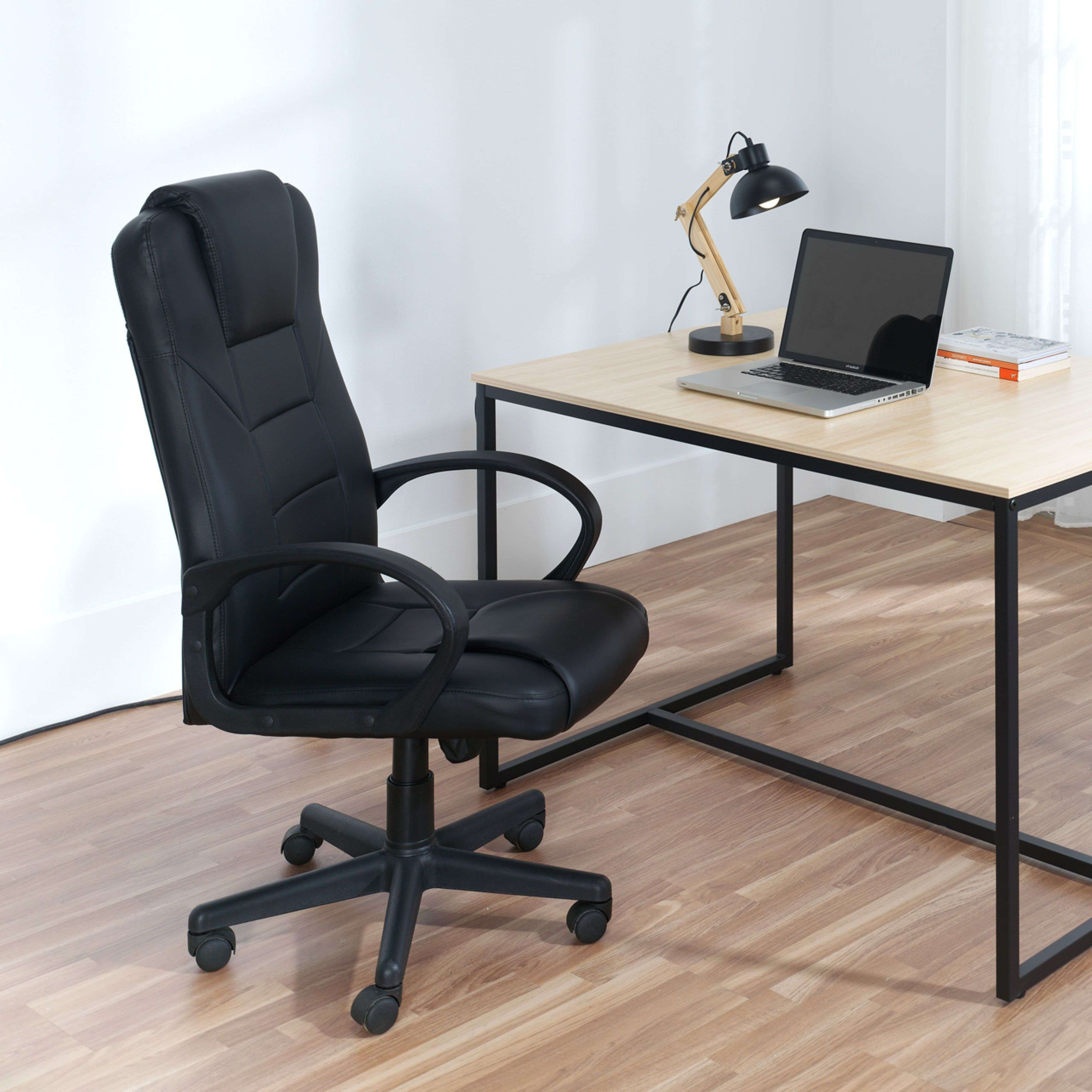 Silla de oficina negra junto a un escritorio de madera con laptop y lámpara.
