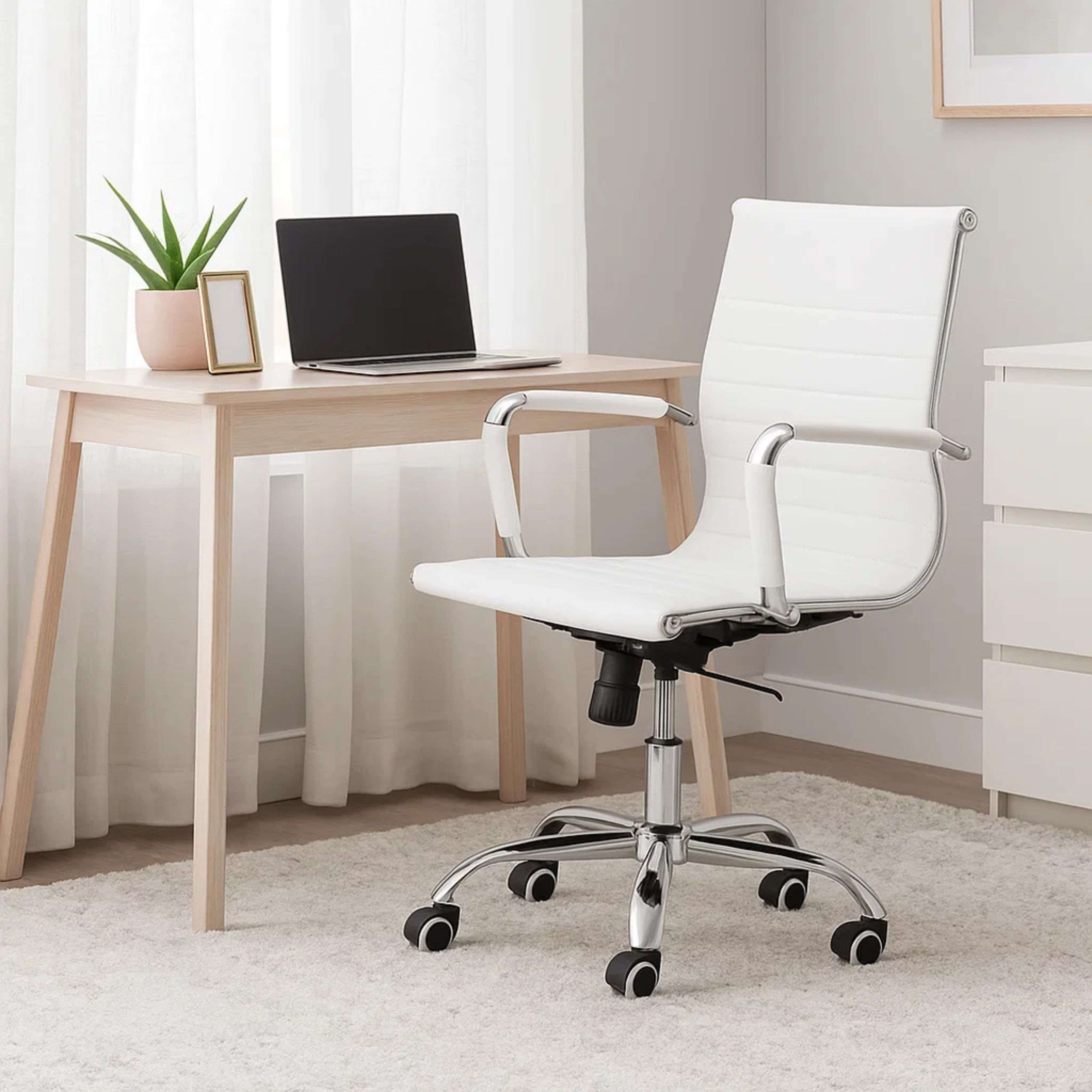 Una silla de oficina blanca con brazos plateados se sienta ante un escritorio de madera clara con portátil.