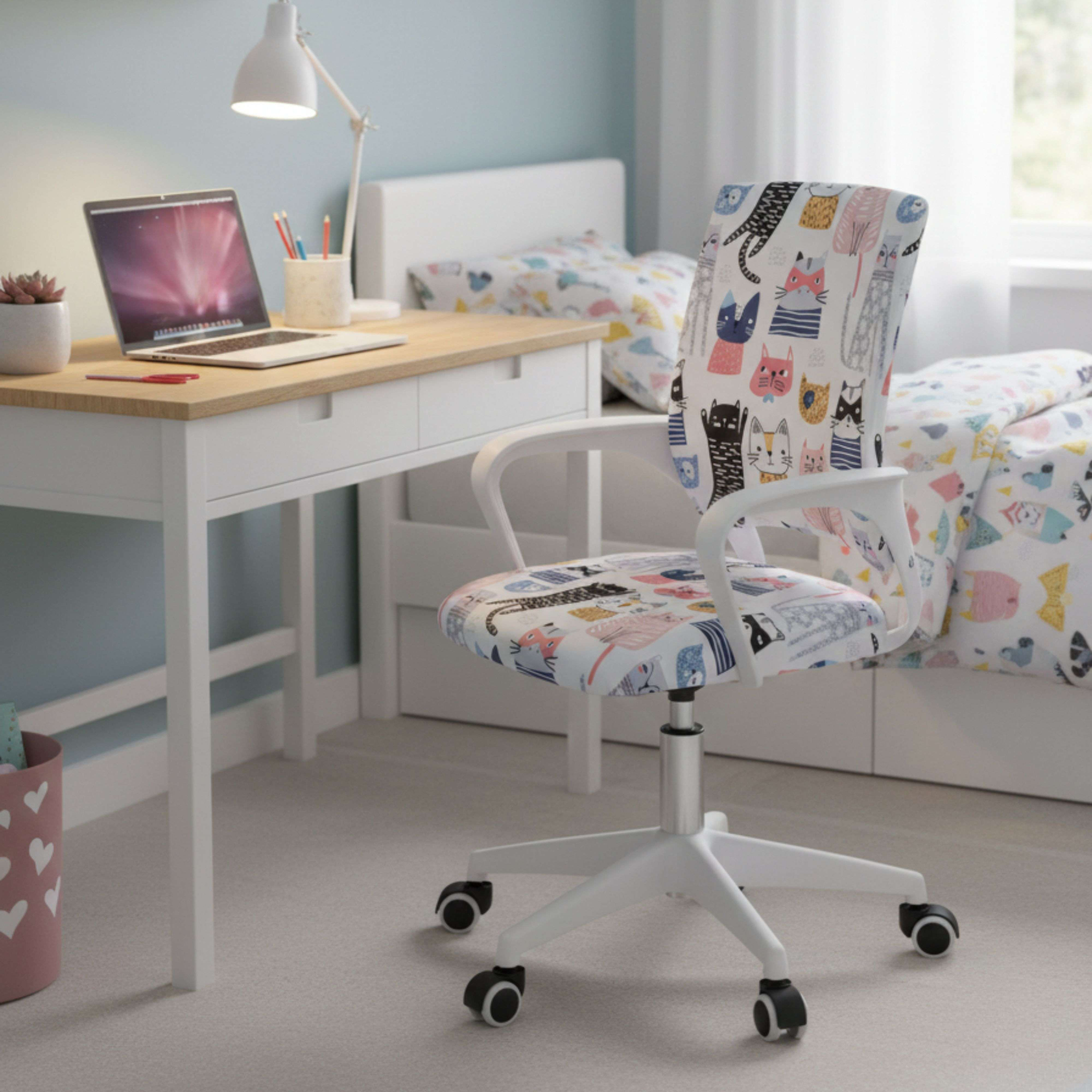 Un escritorio con laptop, sillas y una cama con estampado de gatos.