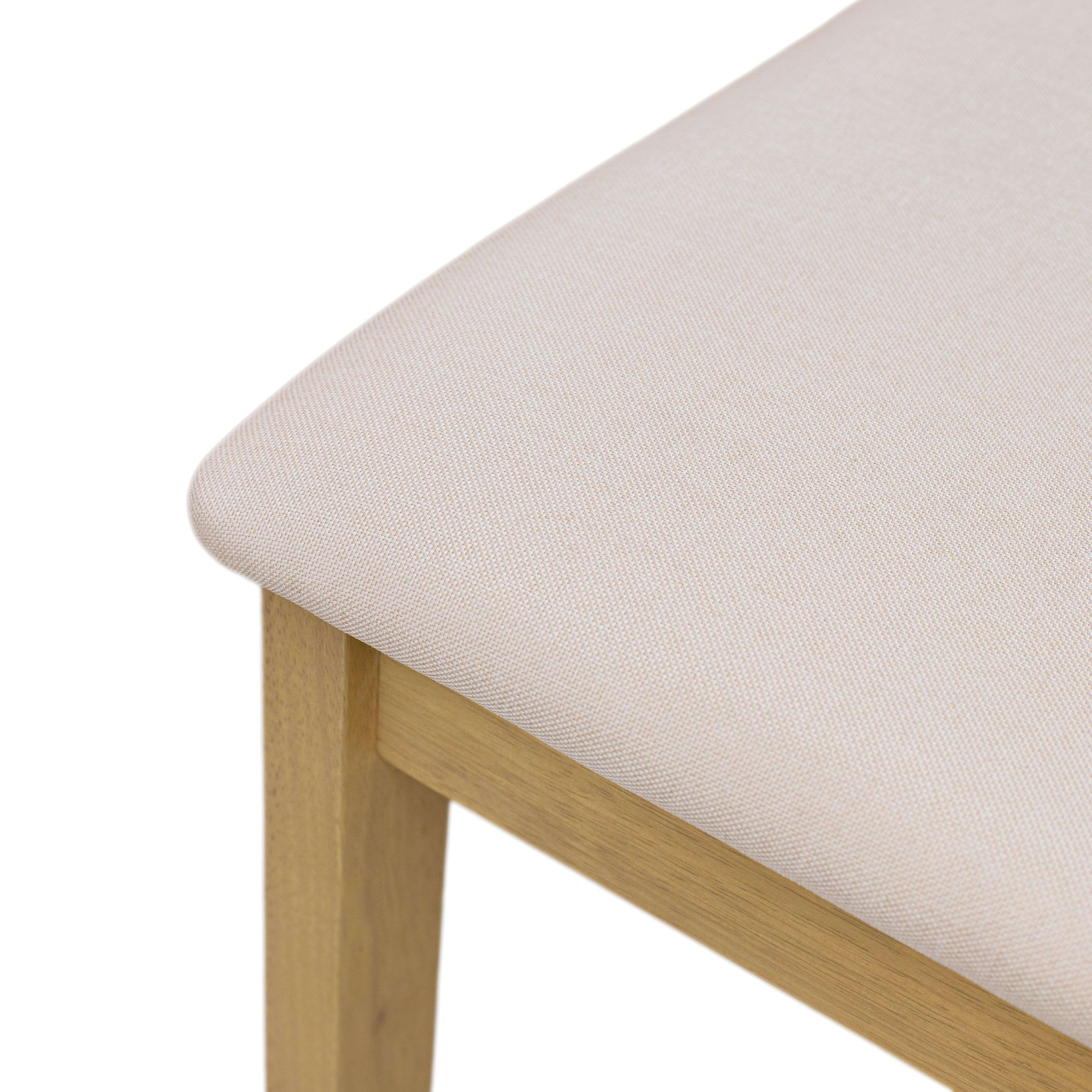 Un asiento tapizado beige y pata de madera de silla sobre fondo blanco.