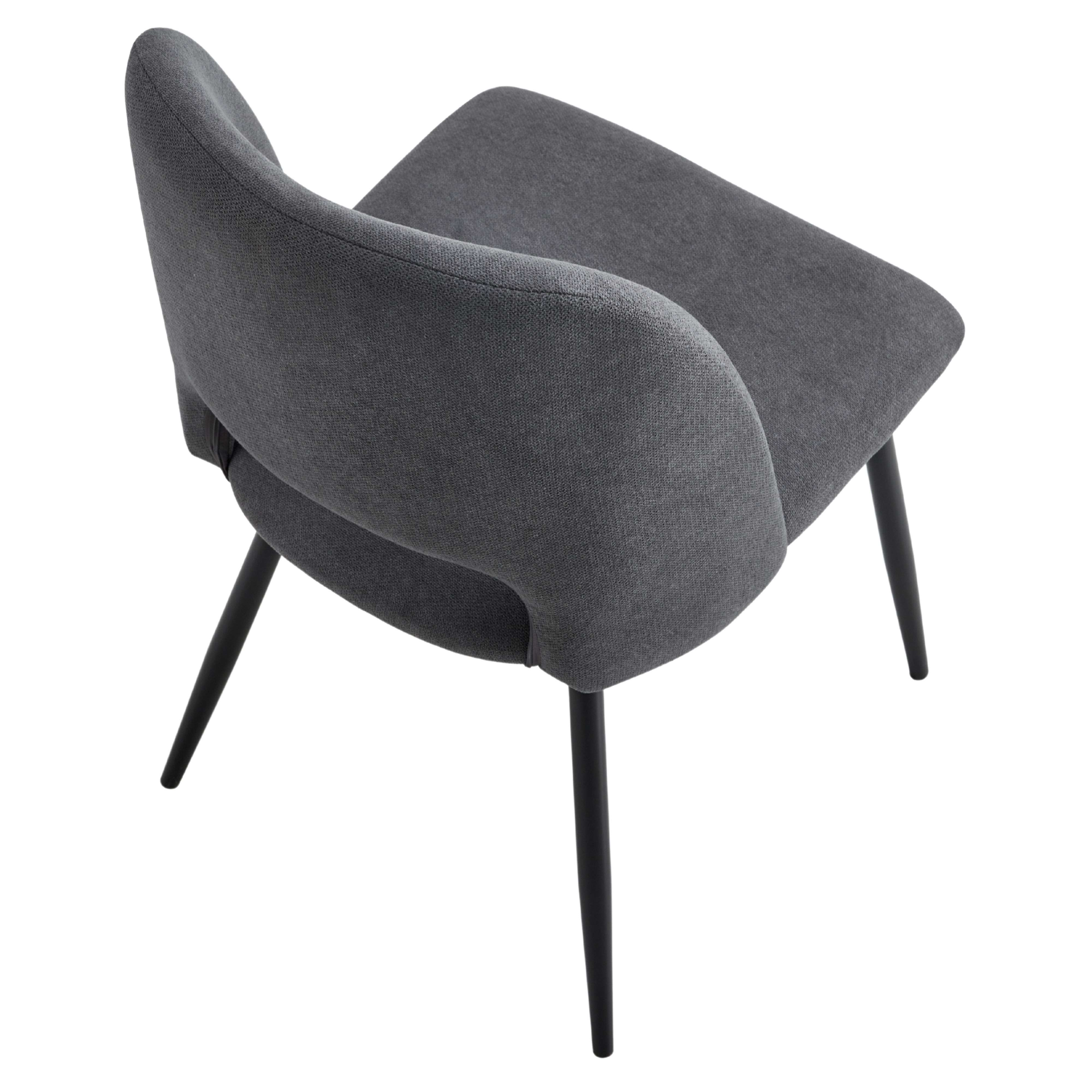 Una silla de tela gris con cuatro patas negras delgadas se muestra sobre fondo blanco.