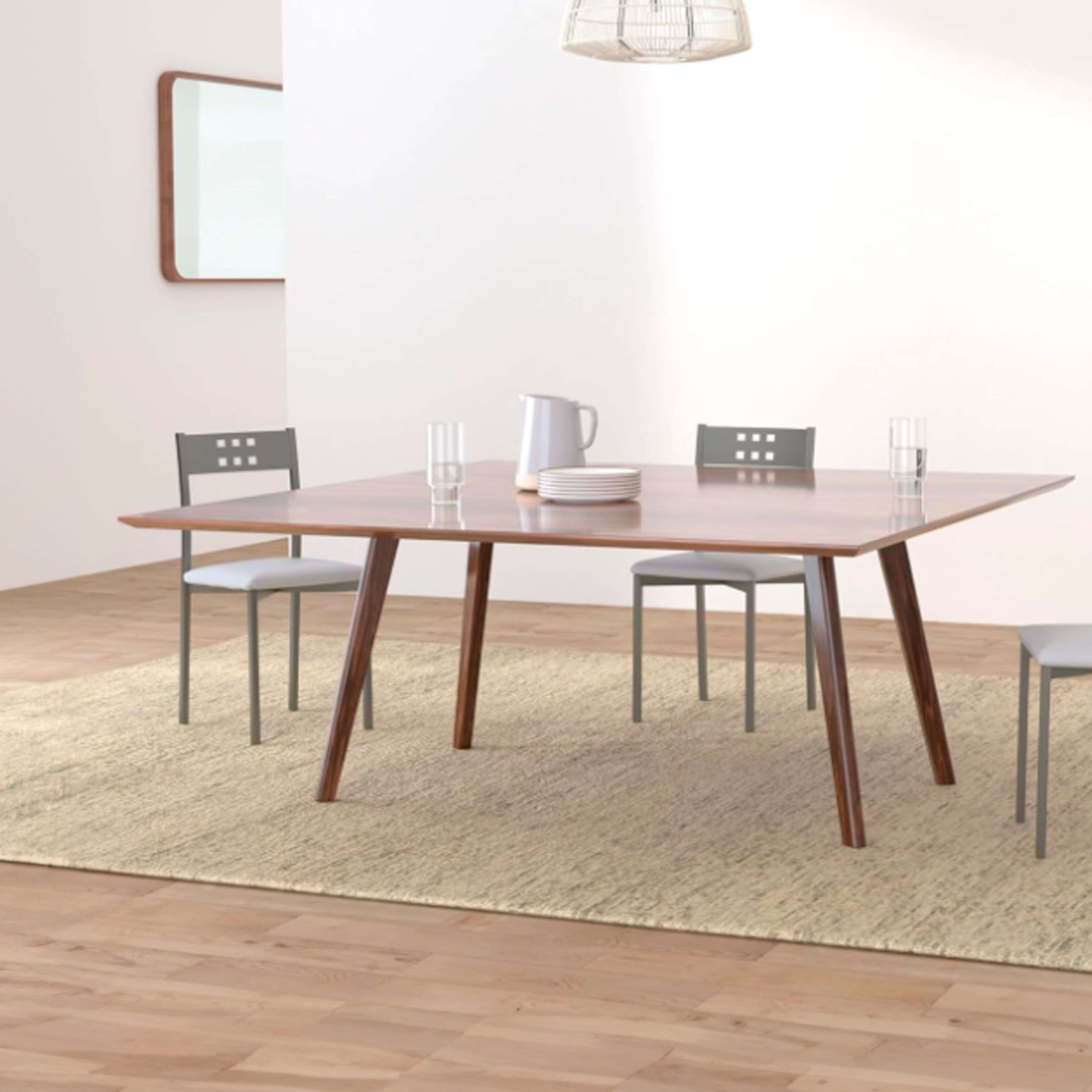 Mesa de comedor de madera con cuatro sillas, jarra, vasos y platos en alfombra.