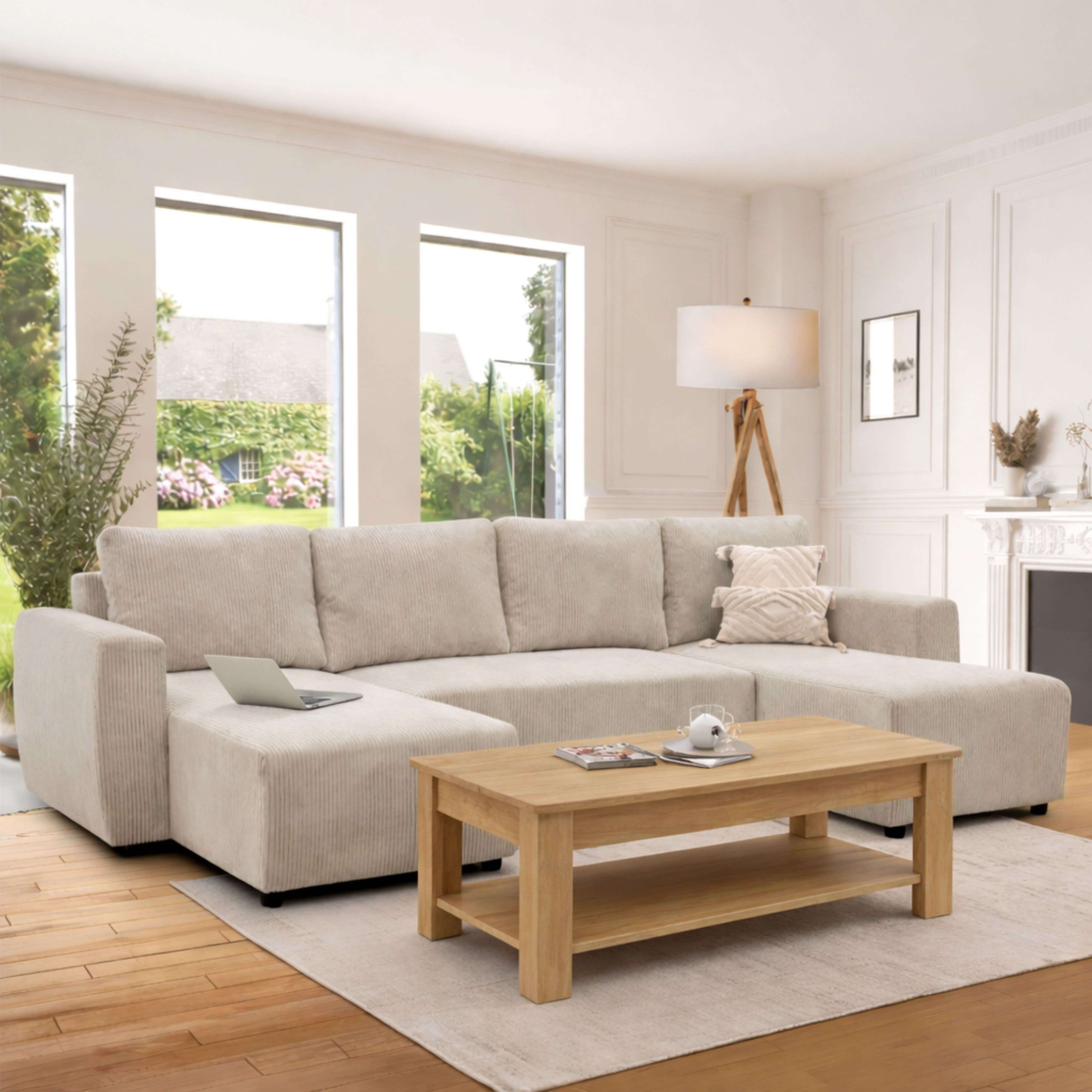 Un sofá seccional beige con mesa de centro de madera, portátil y lámpara.
