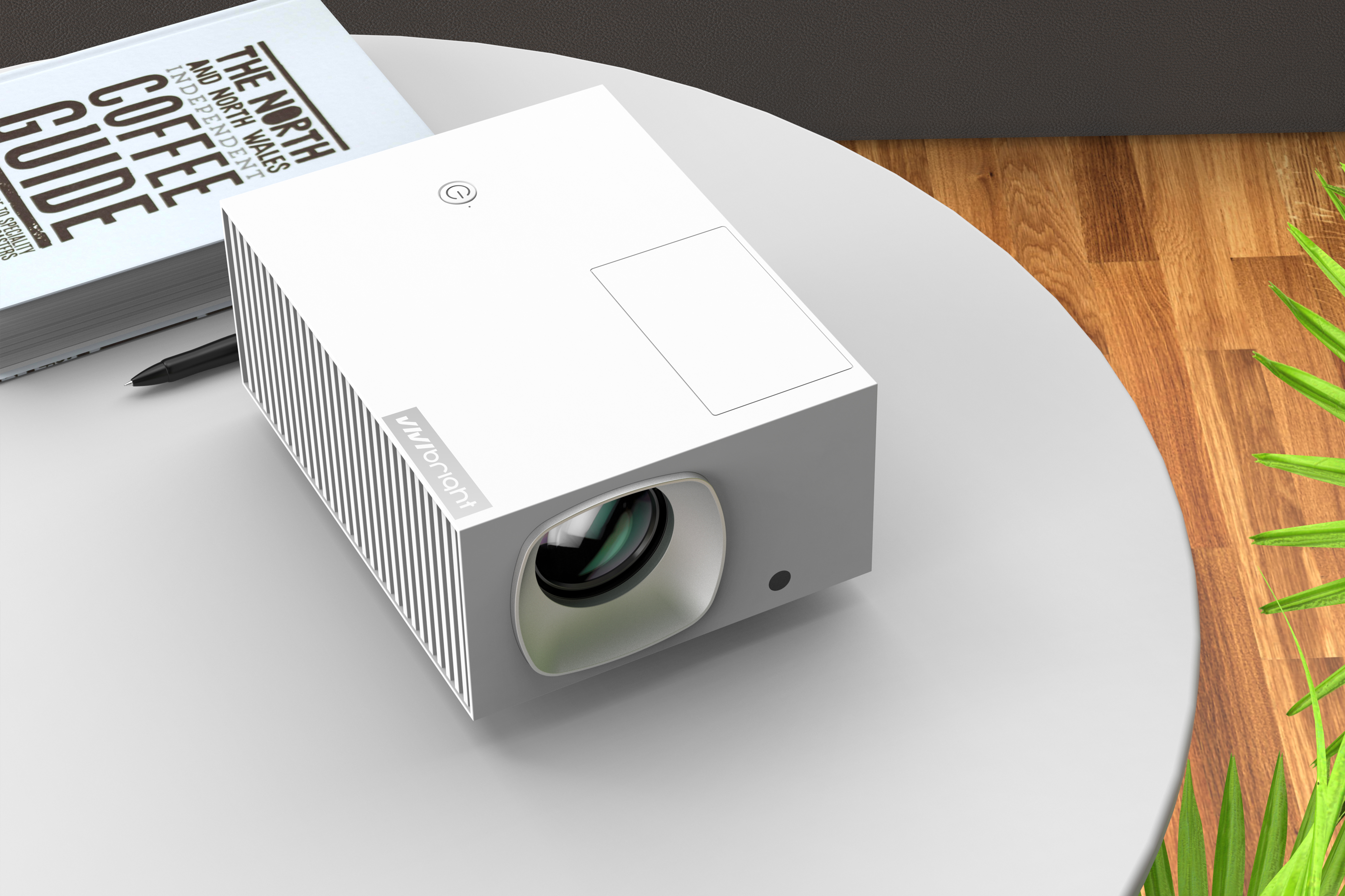 Un proyector blanco se sienta junto a un libro y un bolígrafo sobre una mesa.