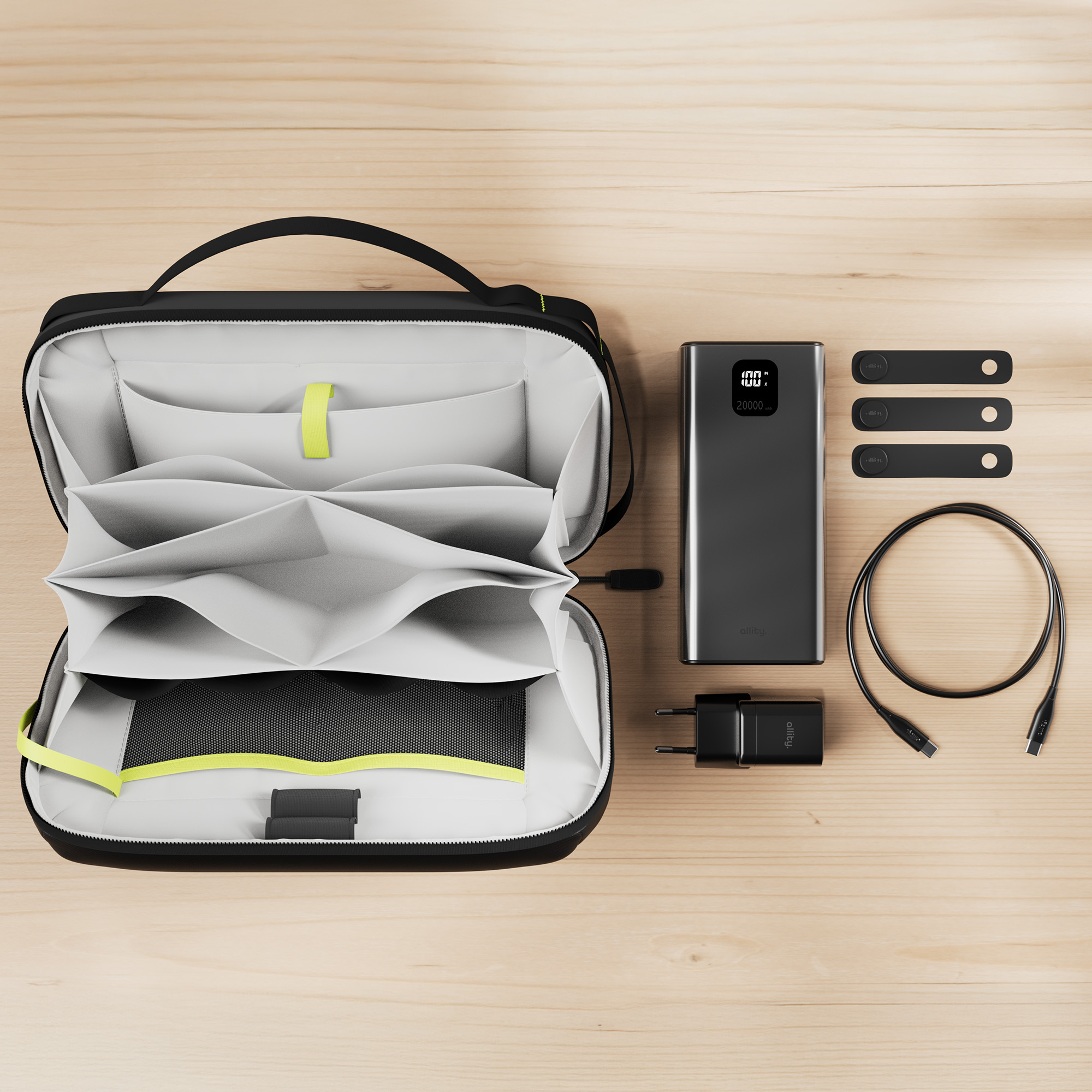 Una borsa nera con scomparti, accanto un power bank, cavo di ricarica, spina e fascette in velcro.