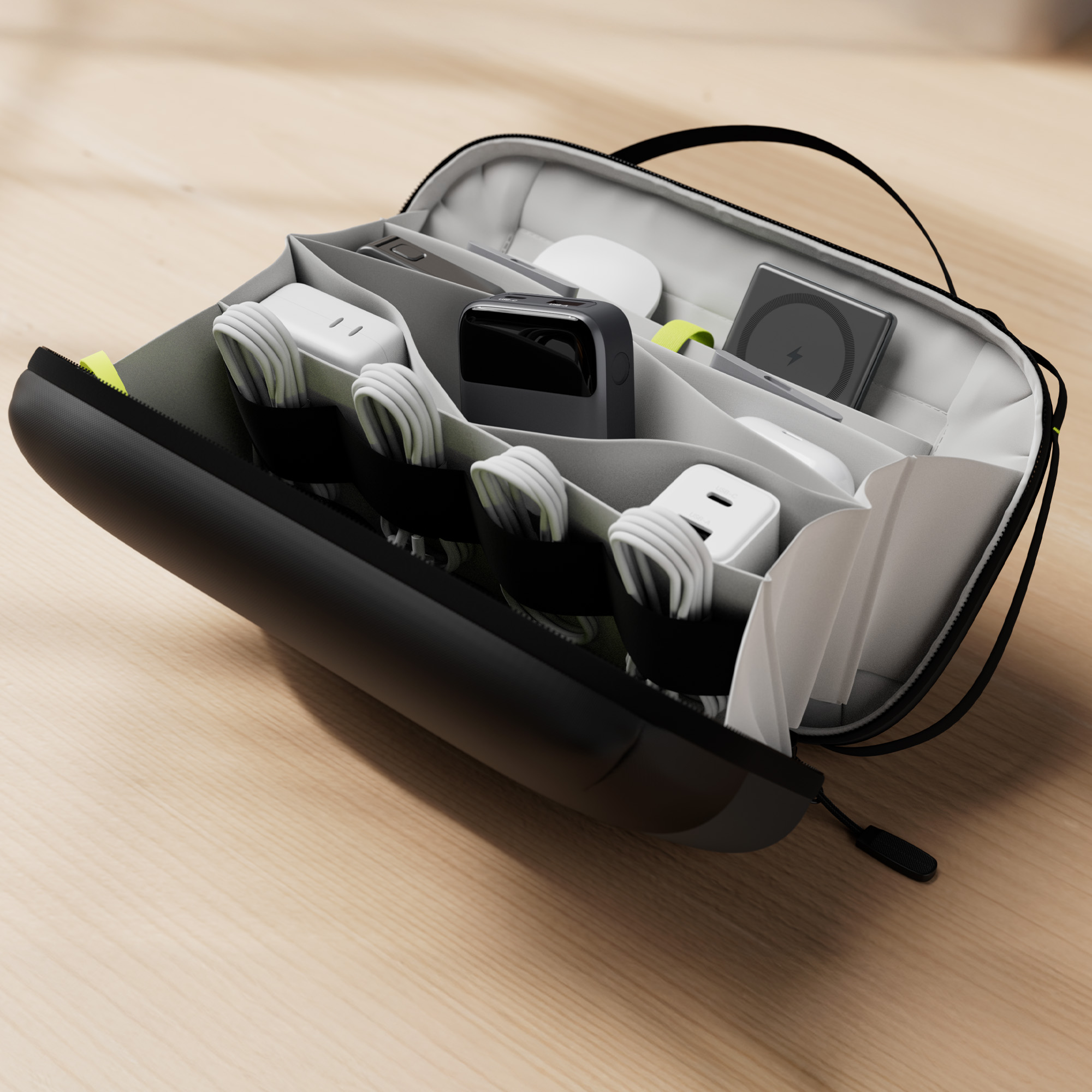 Borsa organizer nera aperta con caricabatterie, cavi e accessori su superficie in legno.