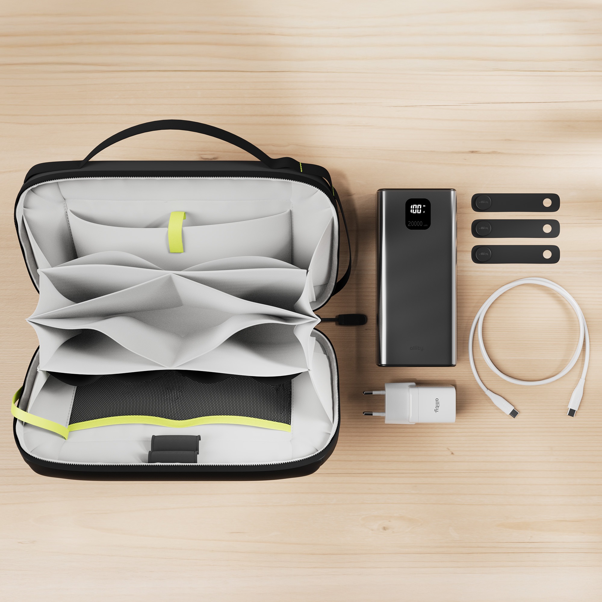 Borsa nera con dettagli verde neon, power bank, caricatore e cavi su superficie in legno.