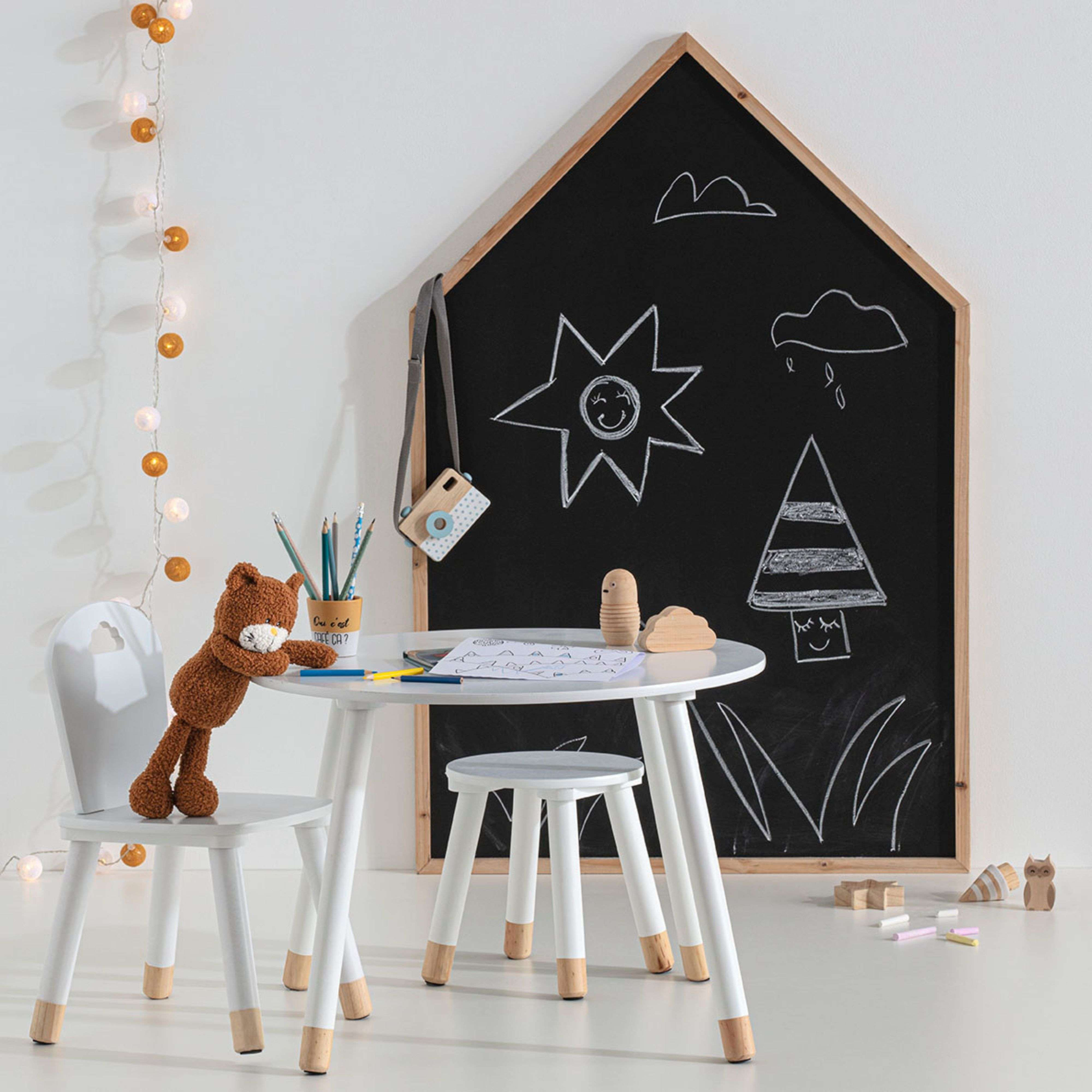 Habitación infantil con pizarra, mesa, silla y juguetes.