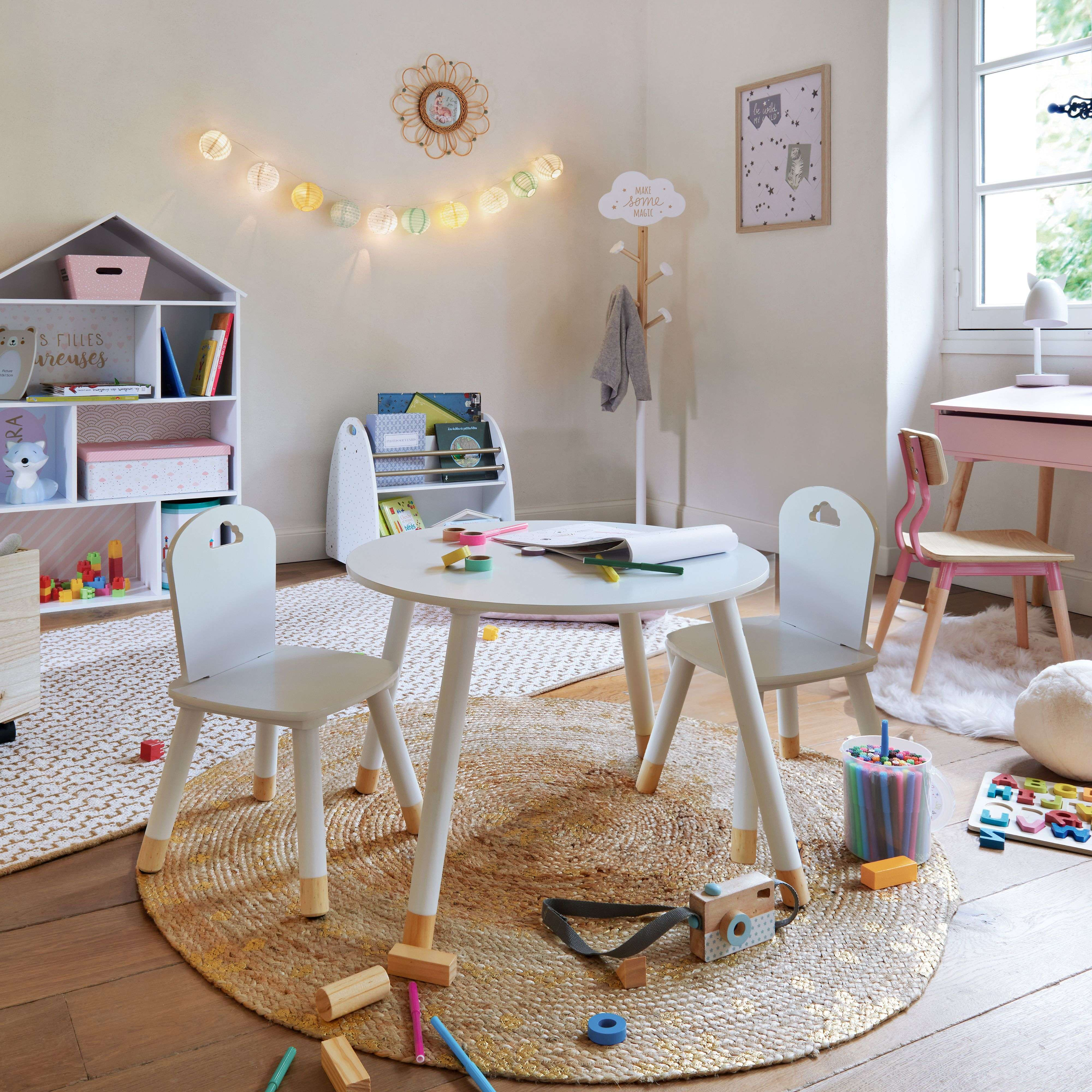 Habitación infantil con mesa, sillas, estanterías, juguetes y lámpara.