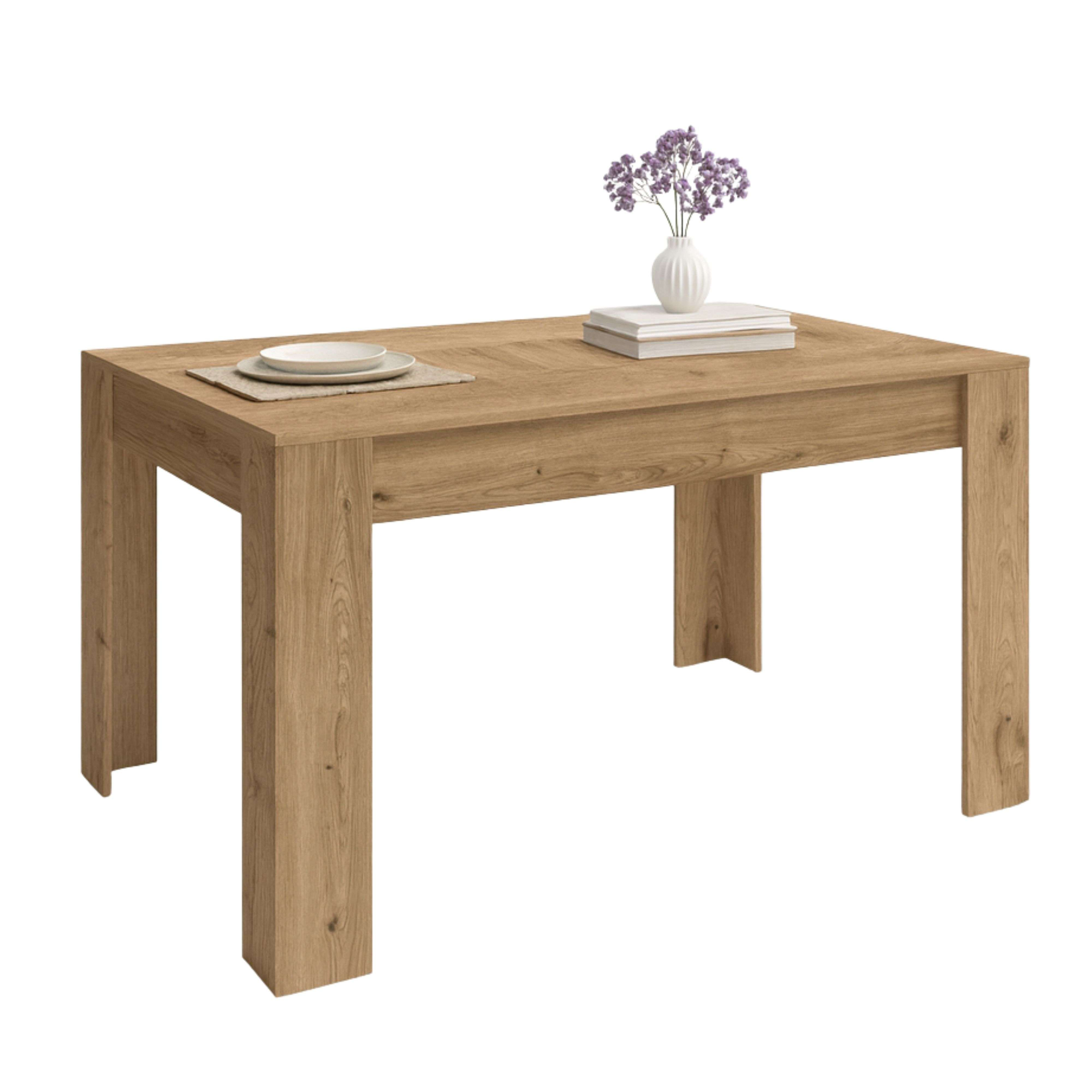 Una mesa de madera clara con dos platos, libros y un jarrón con flores púrpuras.
