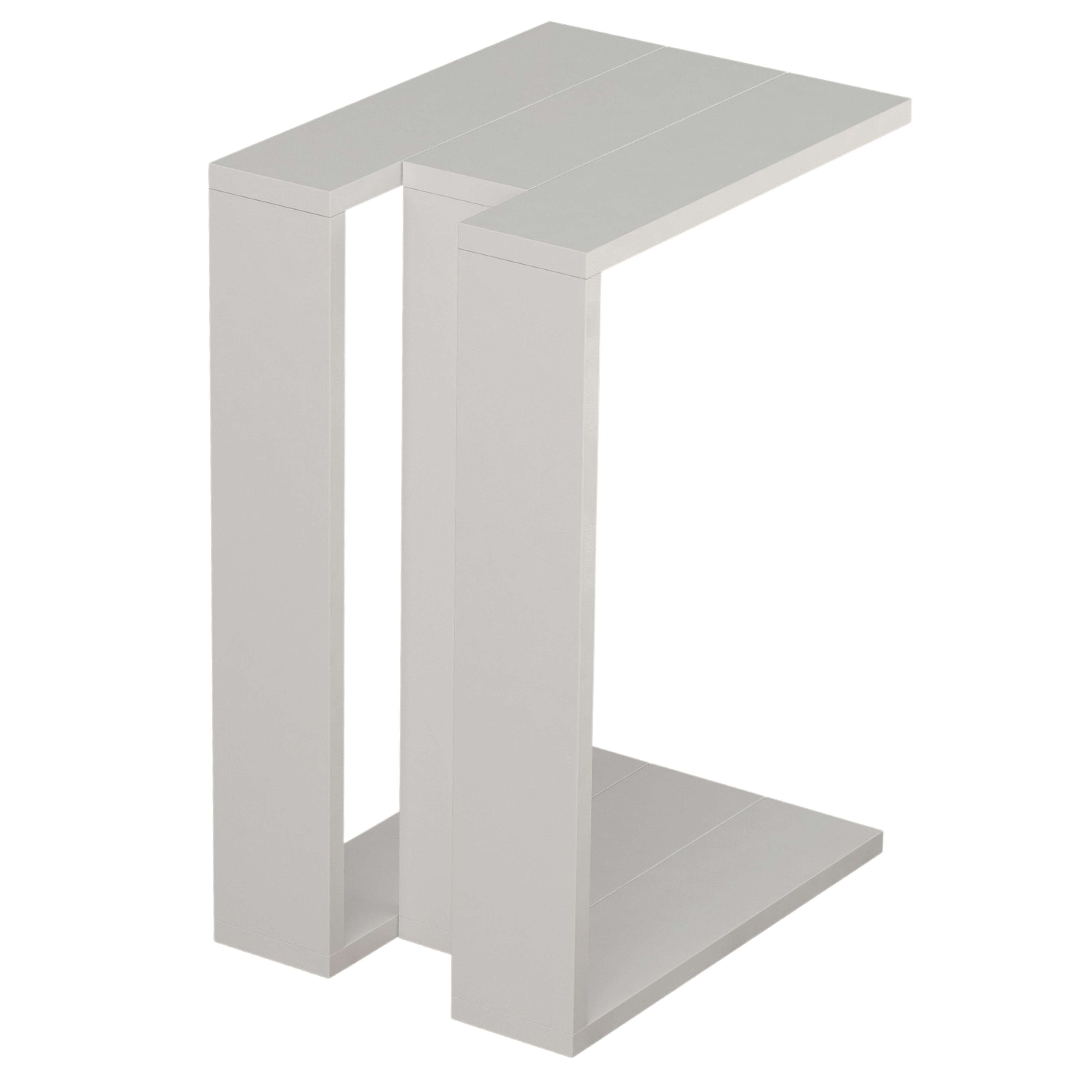 Una mesa auxiliar gris en forma de C con líneas rectas y superficie lisa.