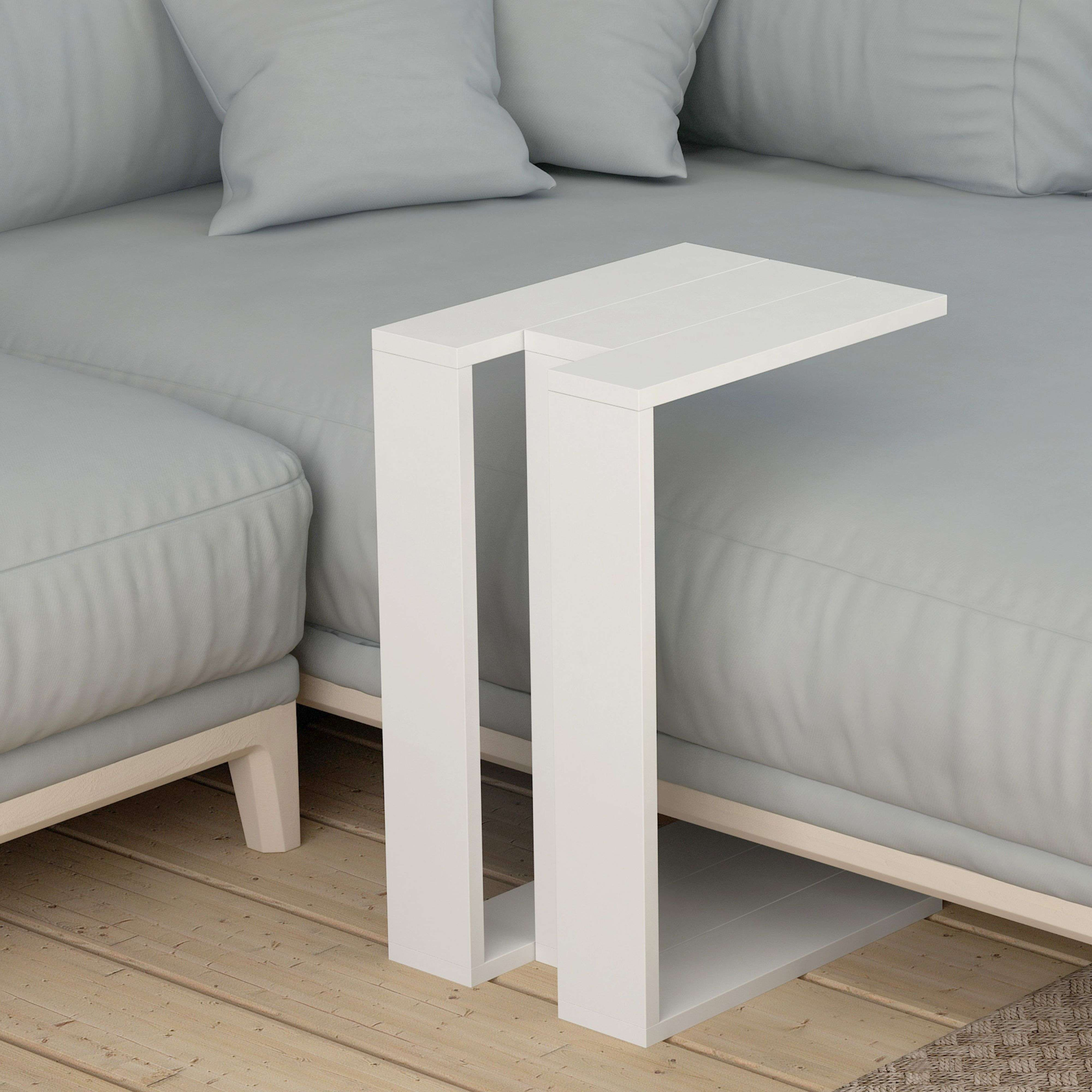 Una mesa en C blanca se sienta junto a un sofá gris sobre un suelo de madera.