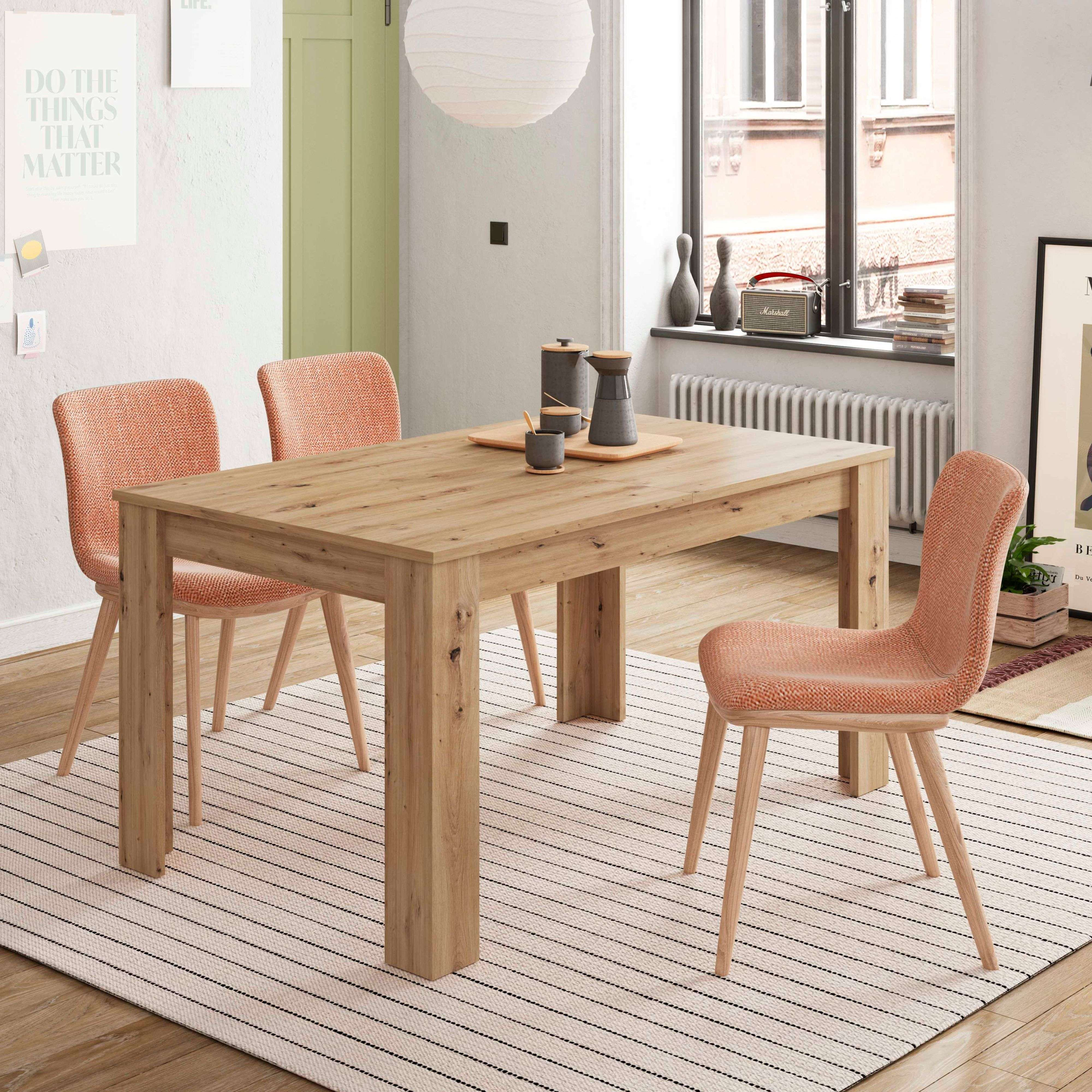 Una mesa de comedor de madera con cuatro sillas naranjas sobre una alfombra de rayas en una sala.
