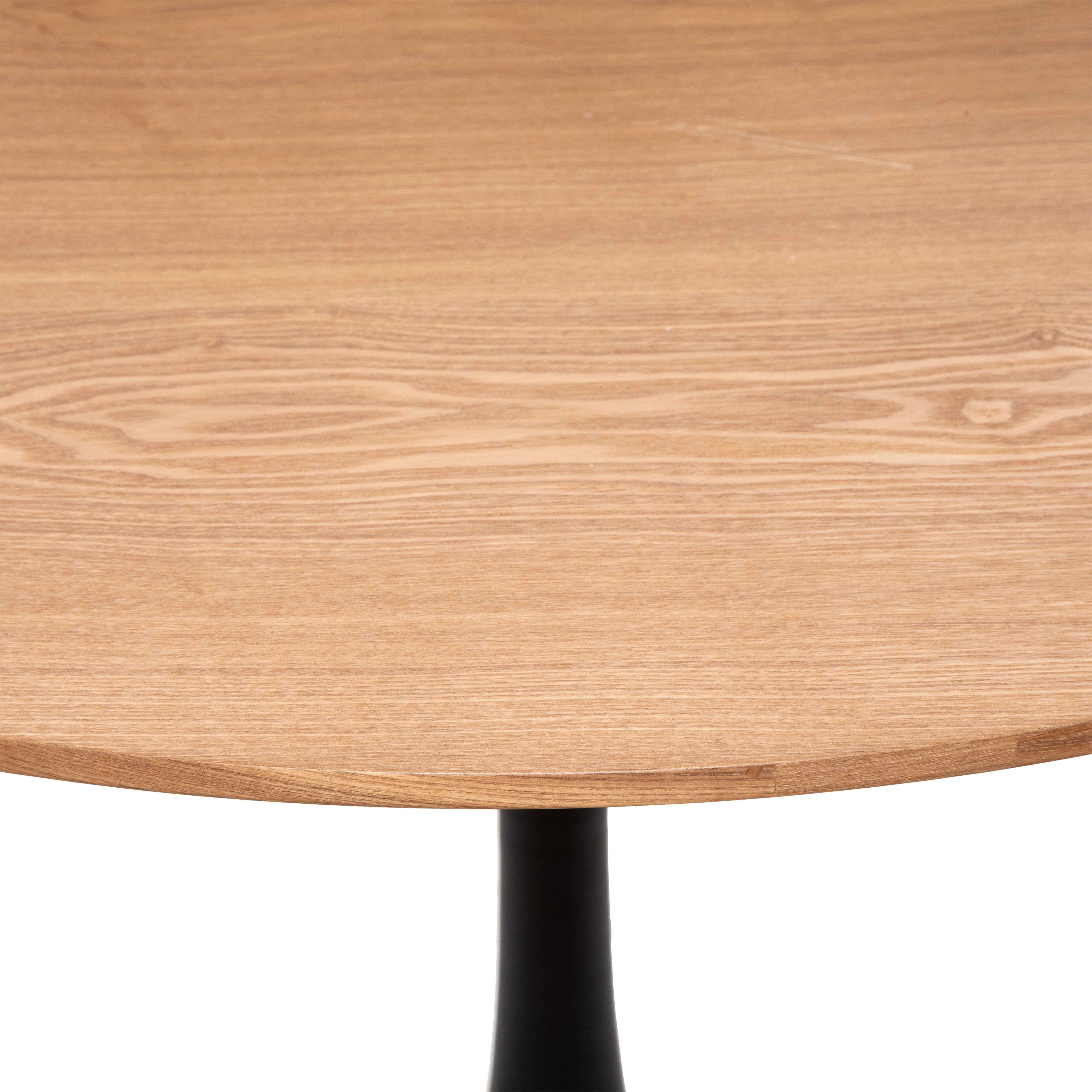 Primer plano de un tablero de mesa redondo de madera con base negra.