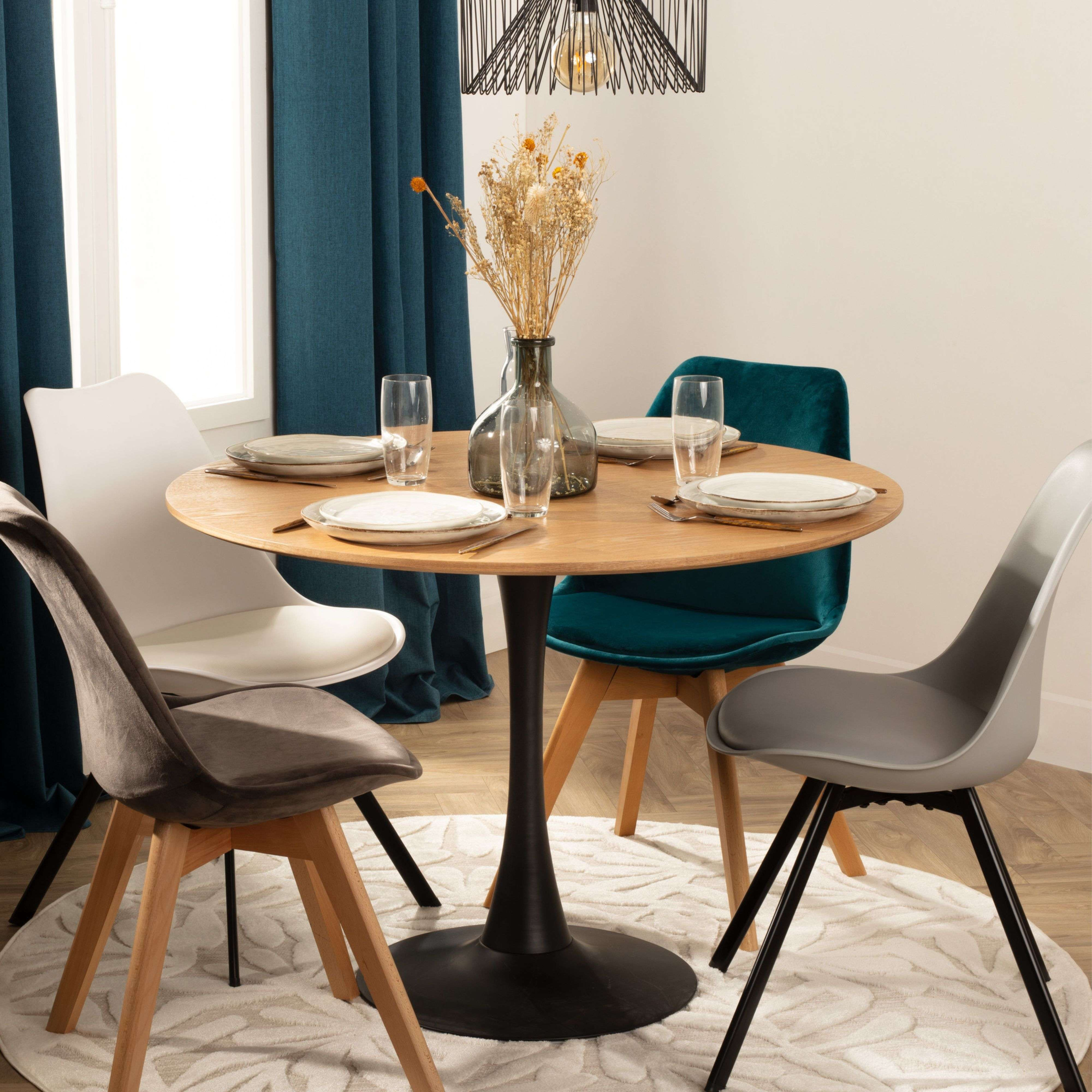 Una mesa redonda de madera con cuatro sillas de diferentes colores.