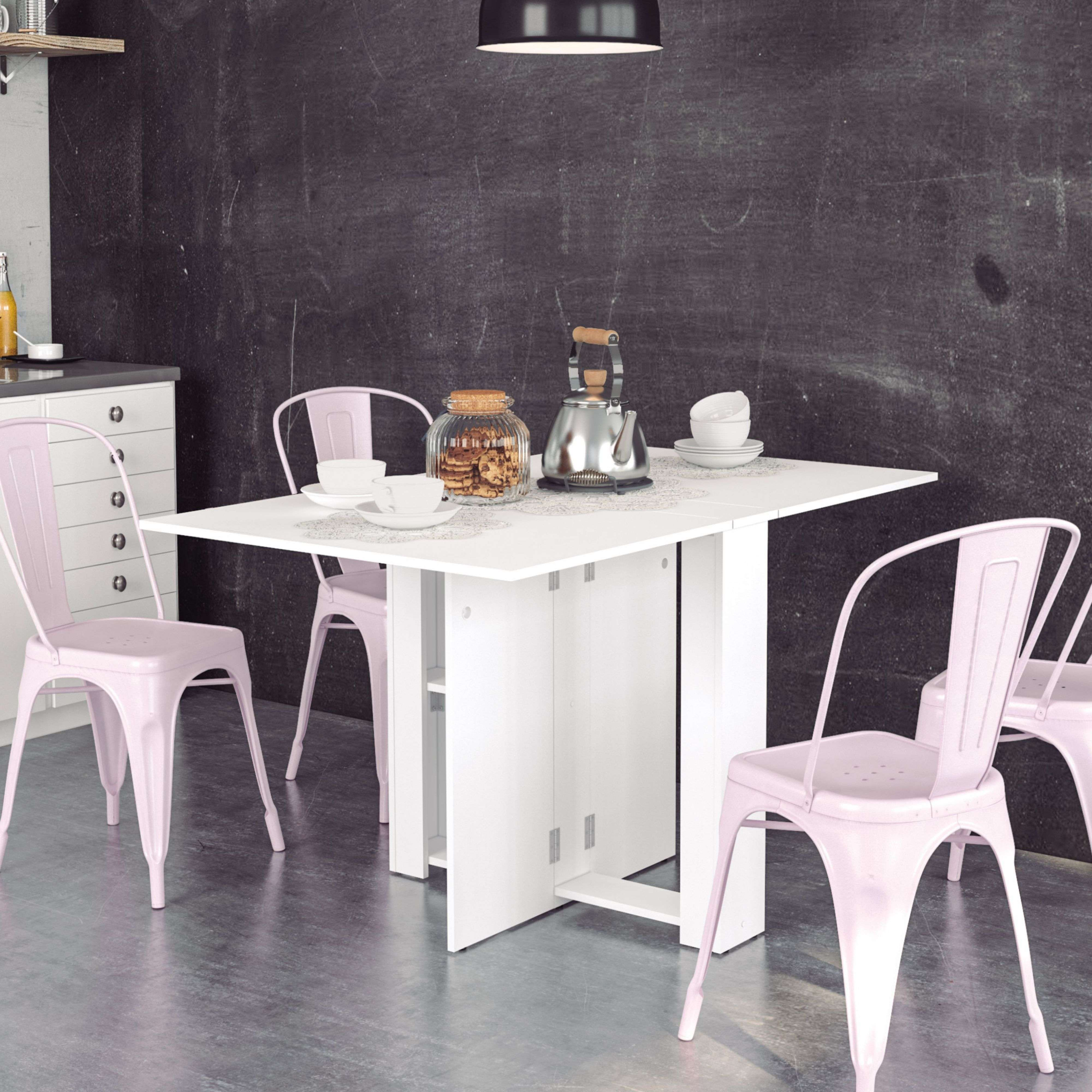 Una mesa blanca con sillas rosas contra una pared de pizarra negra.