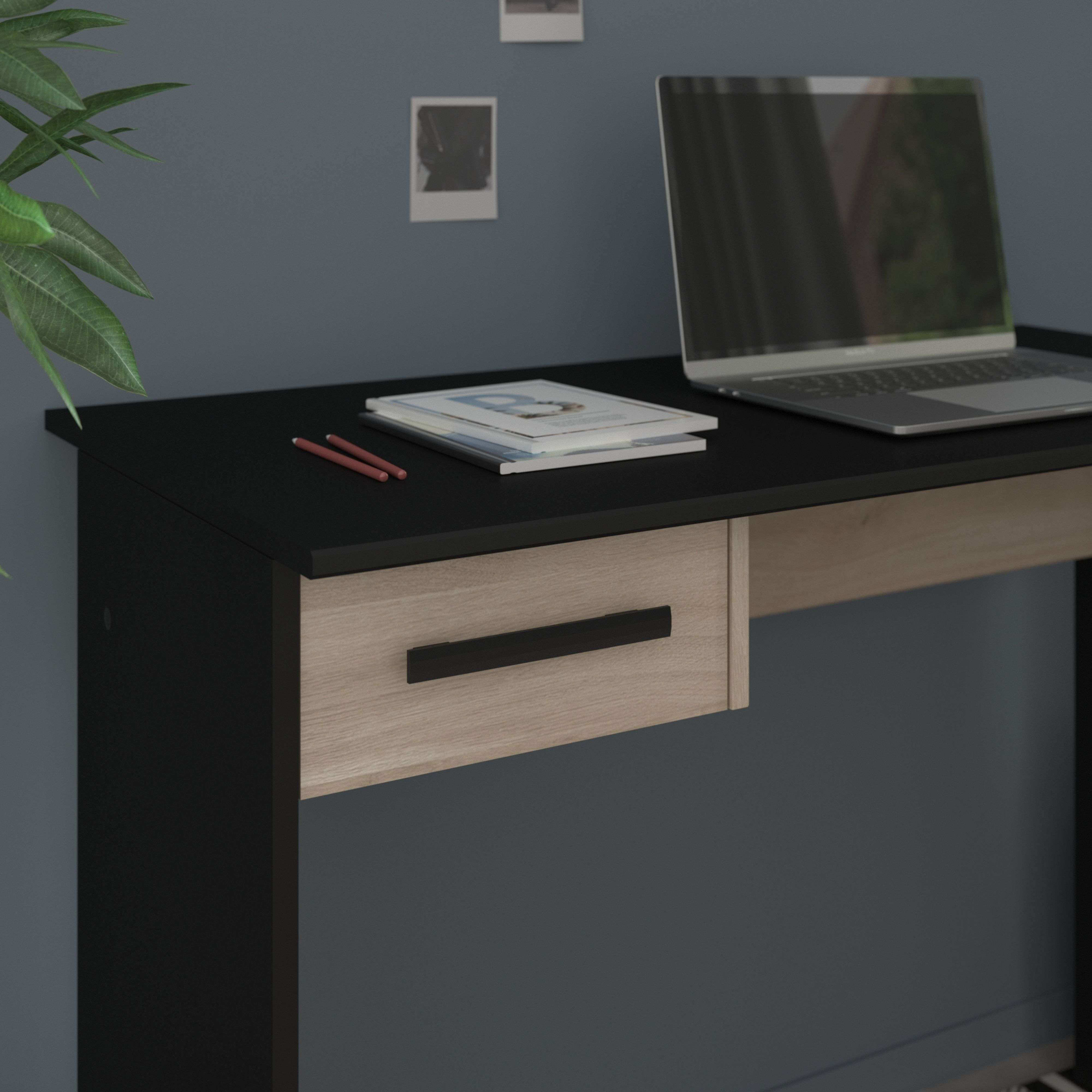 Un portátil sobre un escritorio negro con cajón de madera clara.