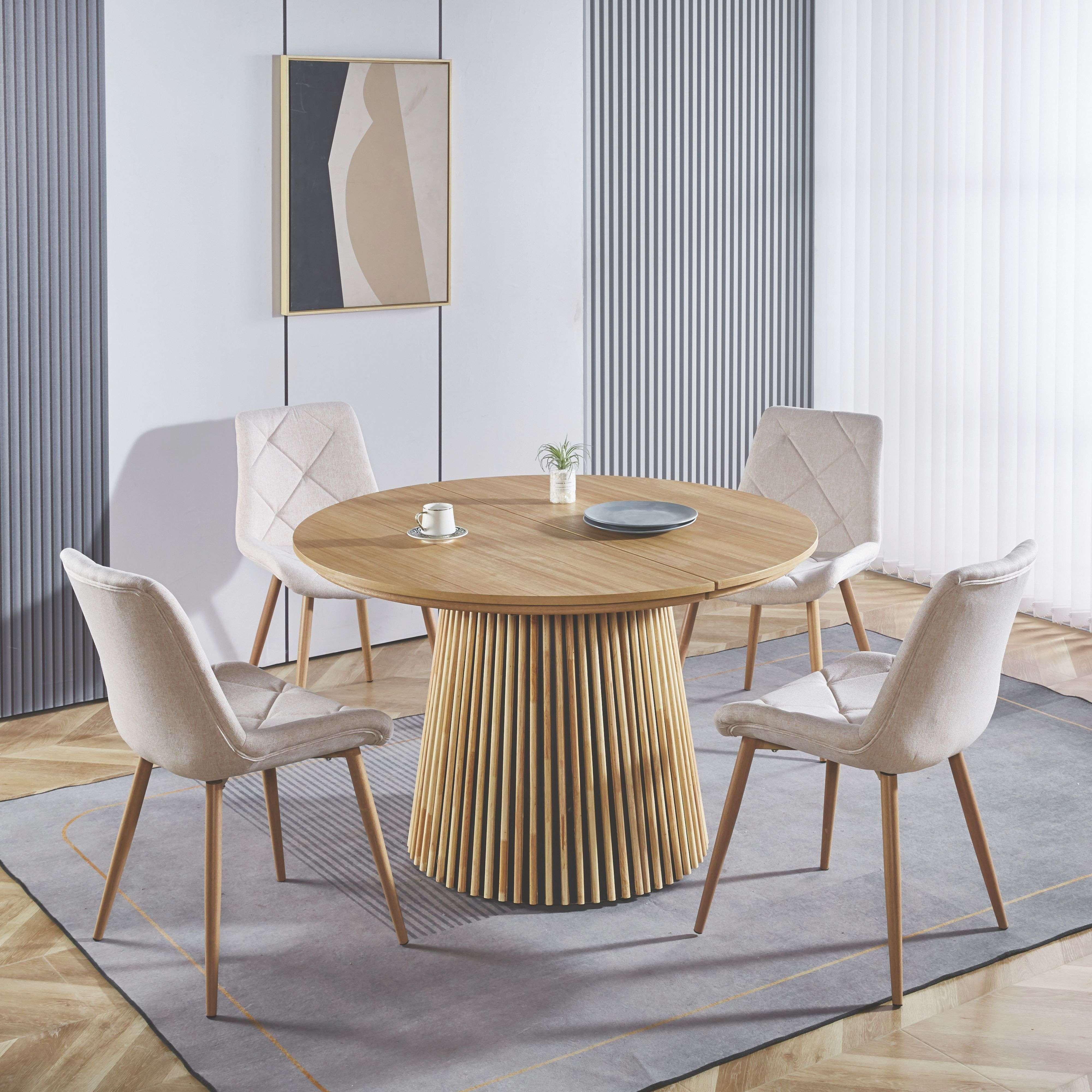 Una mesa redonda de madera con cuatro sillas, decorada con una taza y una planta.