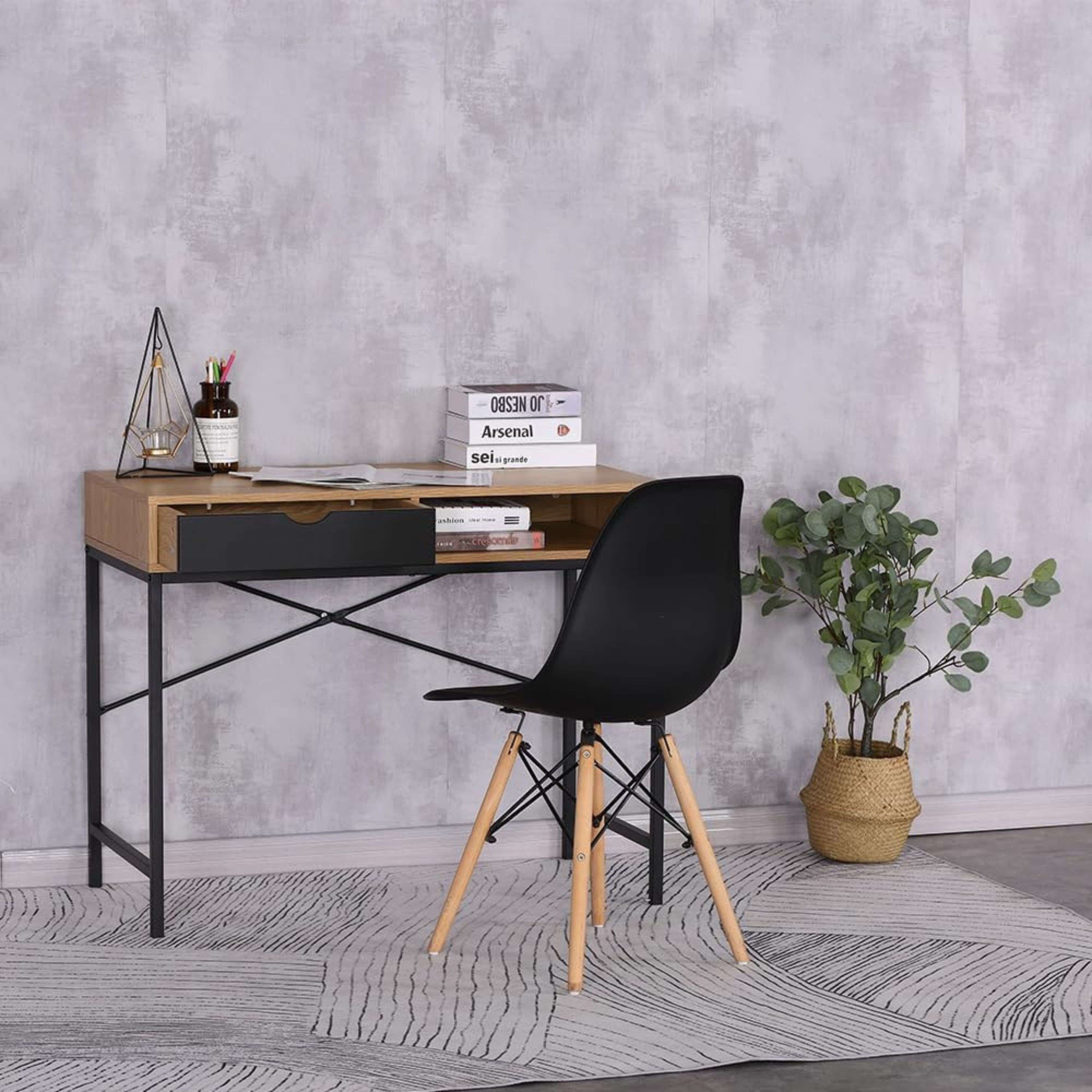 Un escritorio de madera con silla negra, libros y planta.