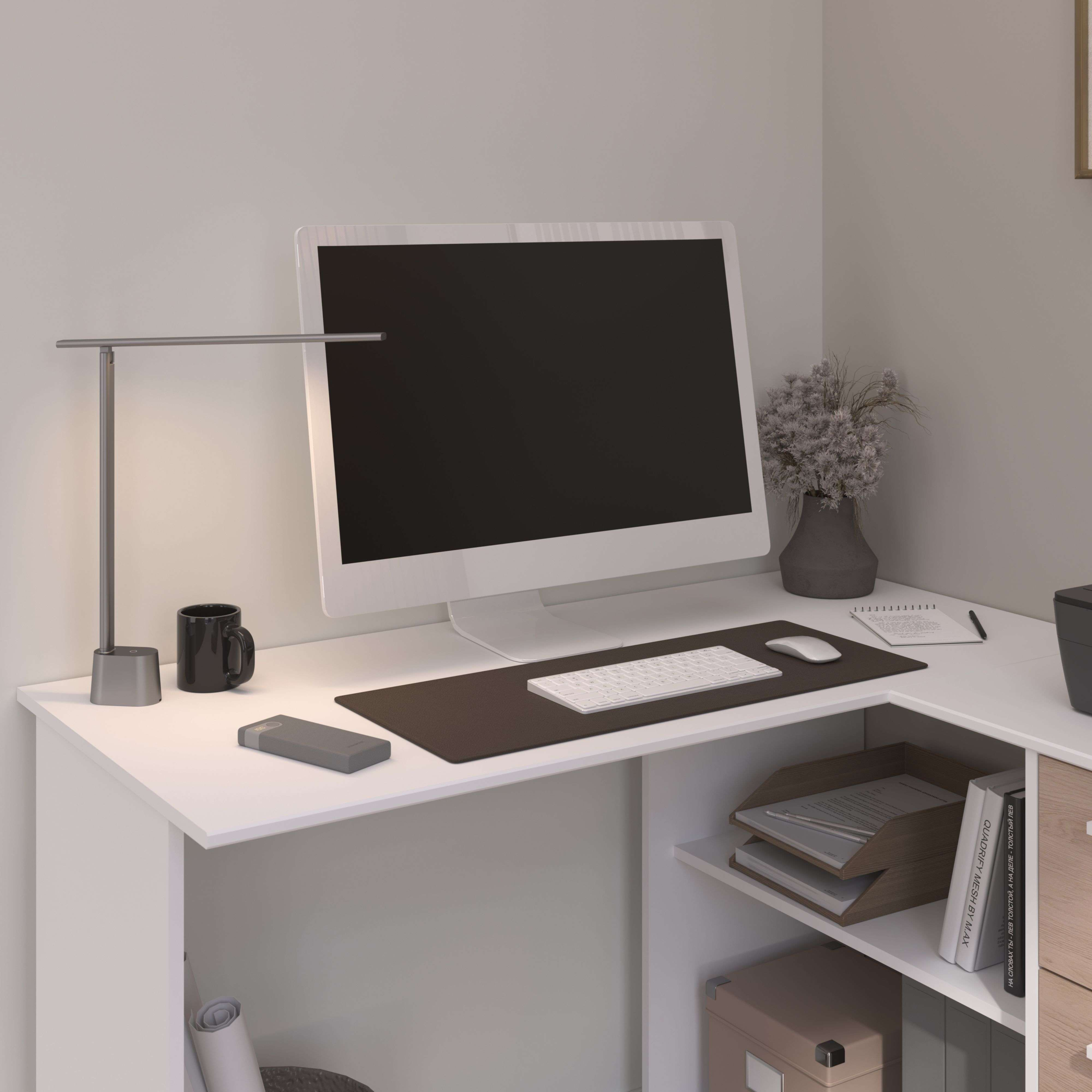Un escritorio moderno con computadora, teclado, ratón, lámpara y taza.