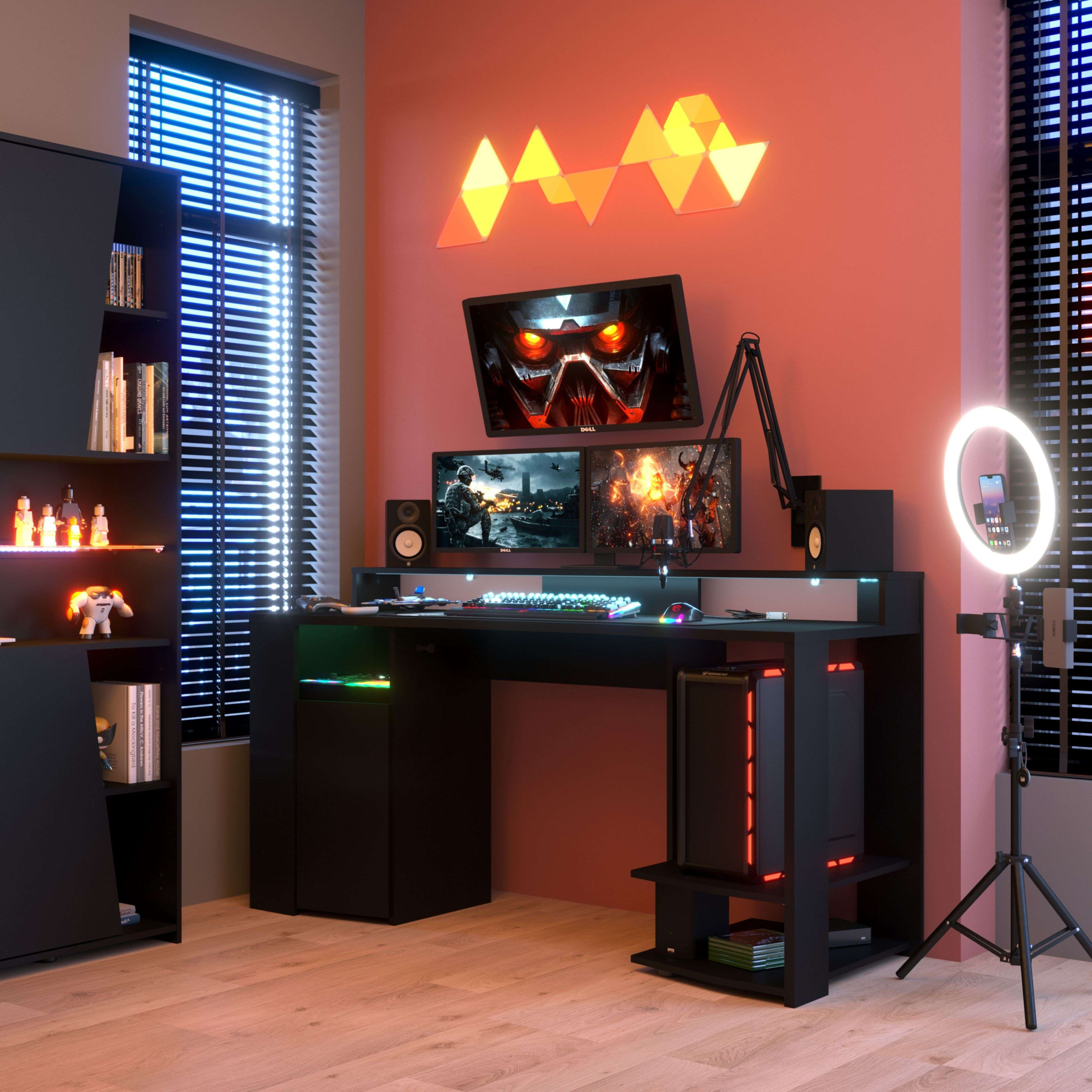 Un escritorio de juegos con tres monitores, PC, teclado y luz de anillo.
