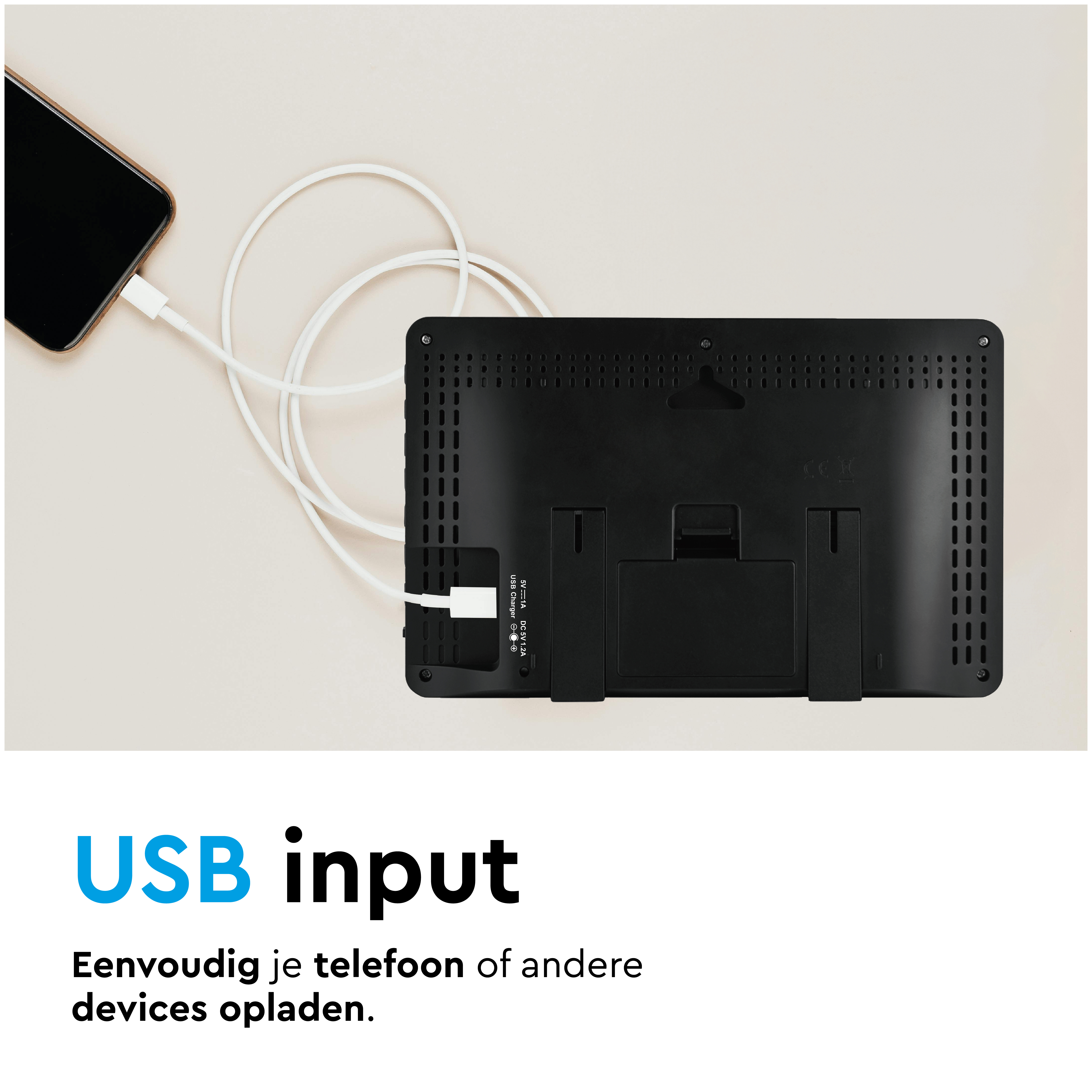 Een smartphone wordt opgeladen via een witte USB-kabel die is aangesloten op een zwart apparaat.