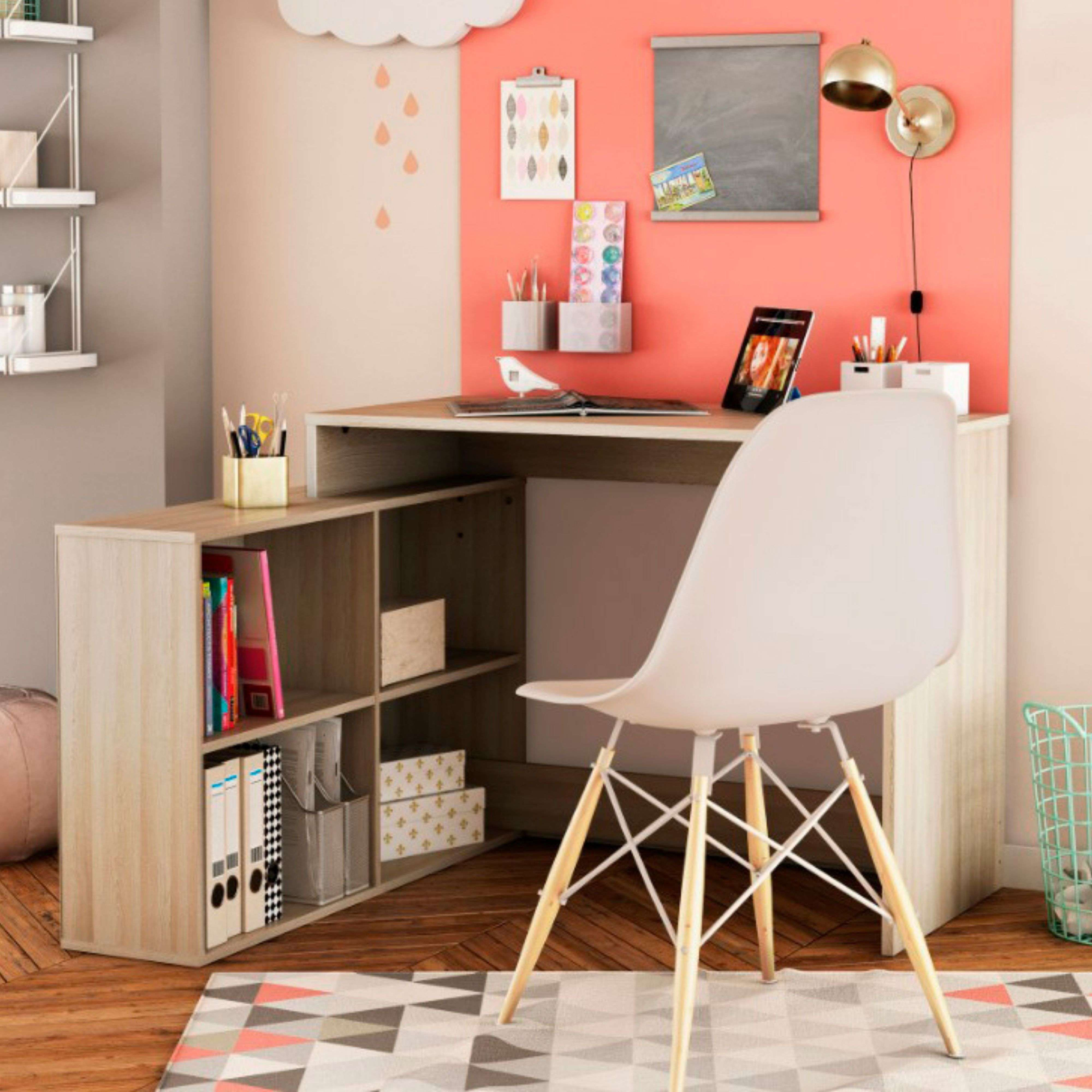 Un escritorio de esquina con estantería, silla blanca y decoración.
