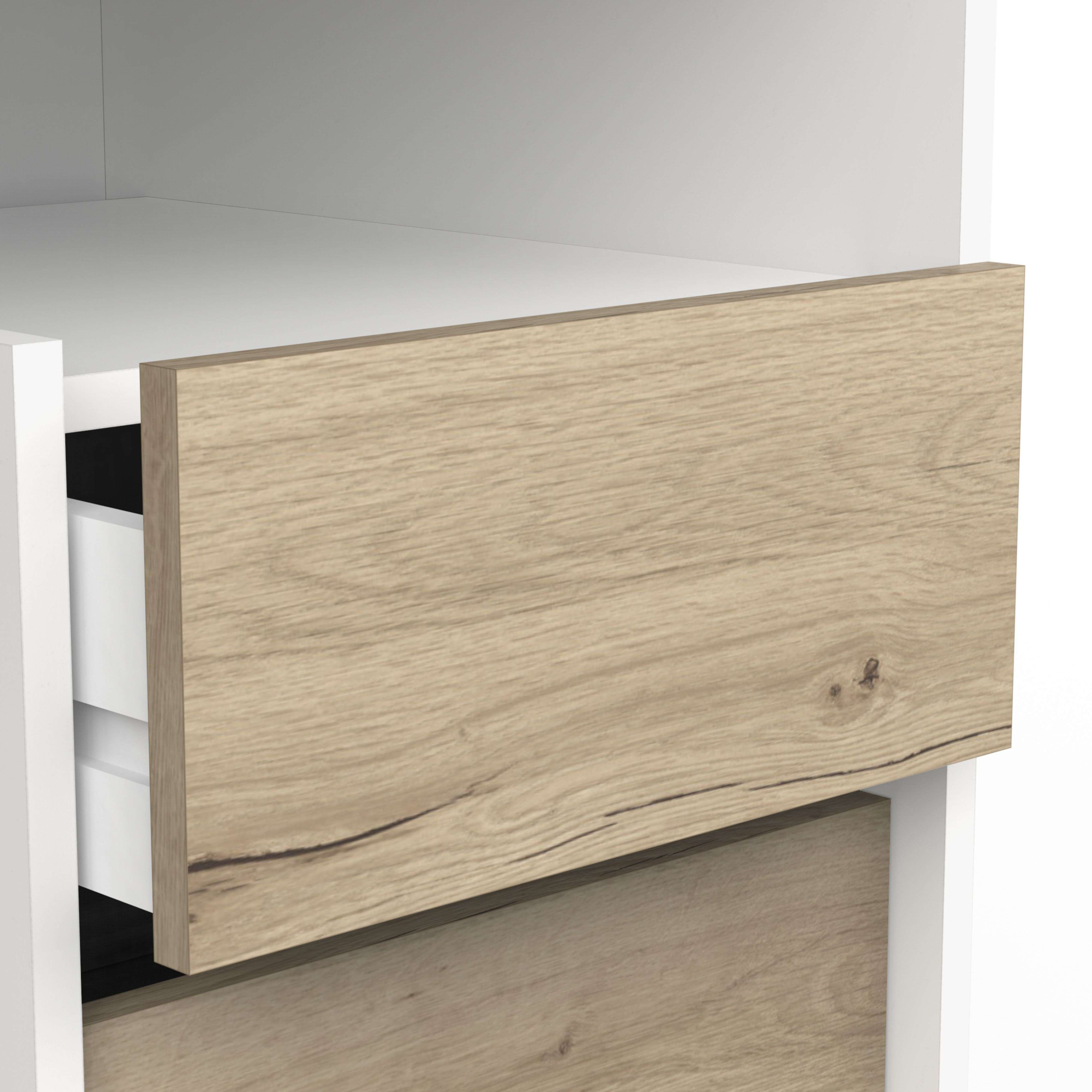 Un cajón extraído de un mueble blanco, mostrando un frente de cajón con veta de madera.