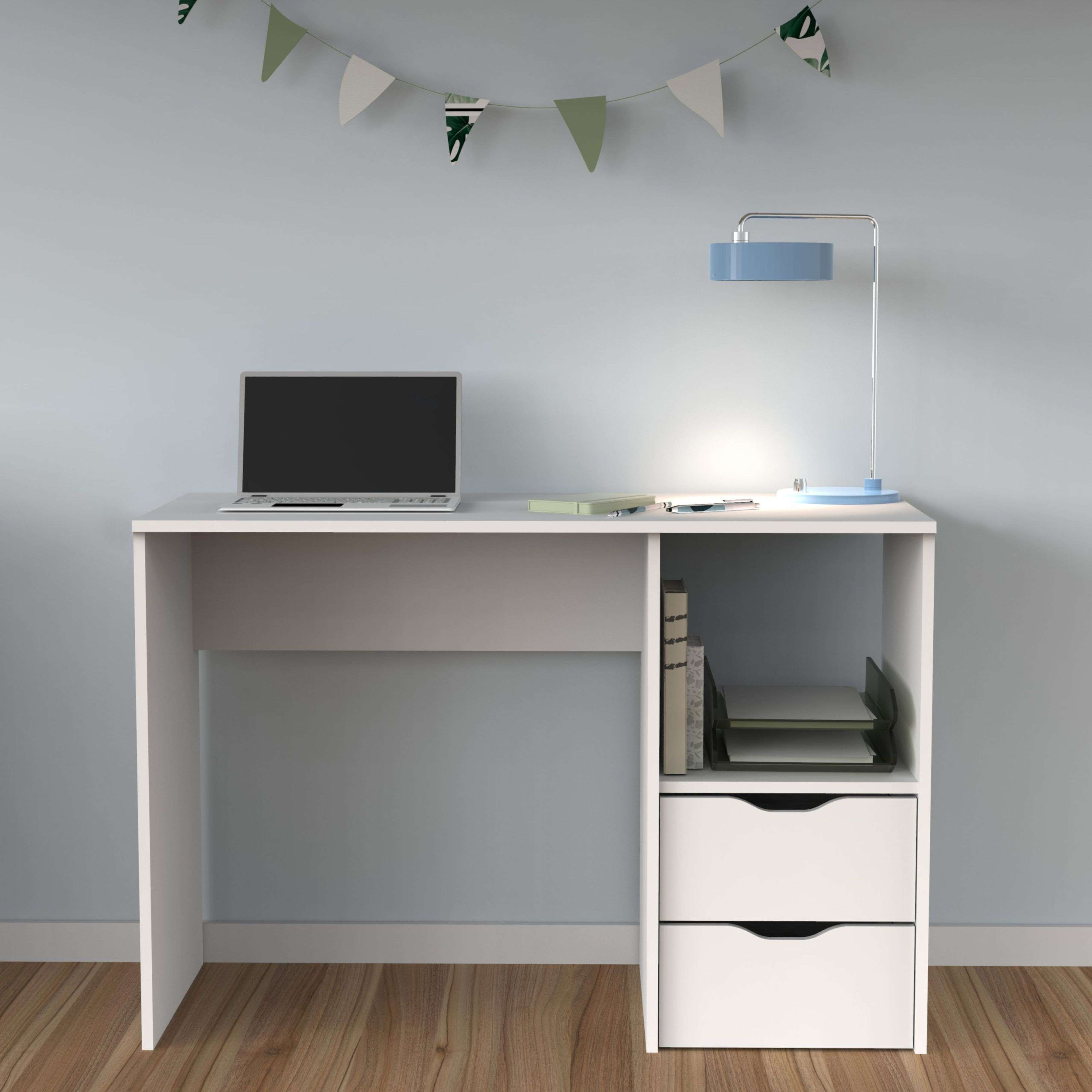 Un escritorio blanco con portátil, lámpara y libros frente a una pared azul.