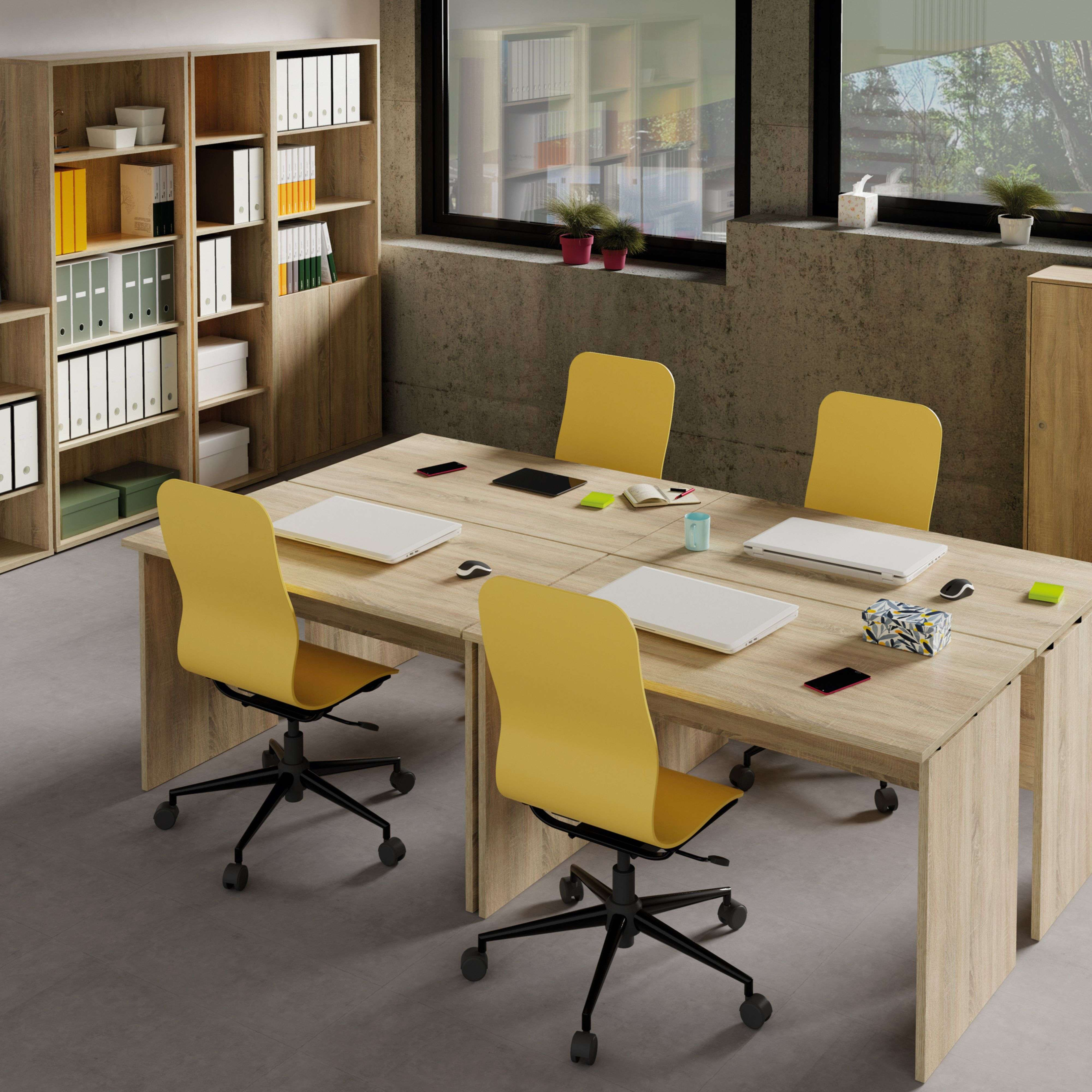 Una oficina moderna con mesa de madera, sillas amarillas, portátiles y carpetas.