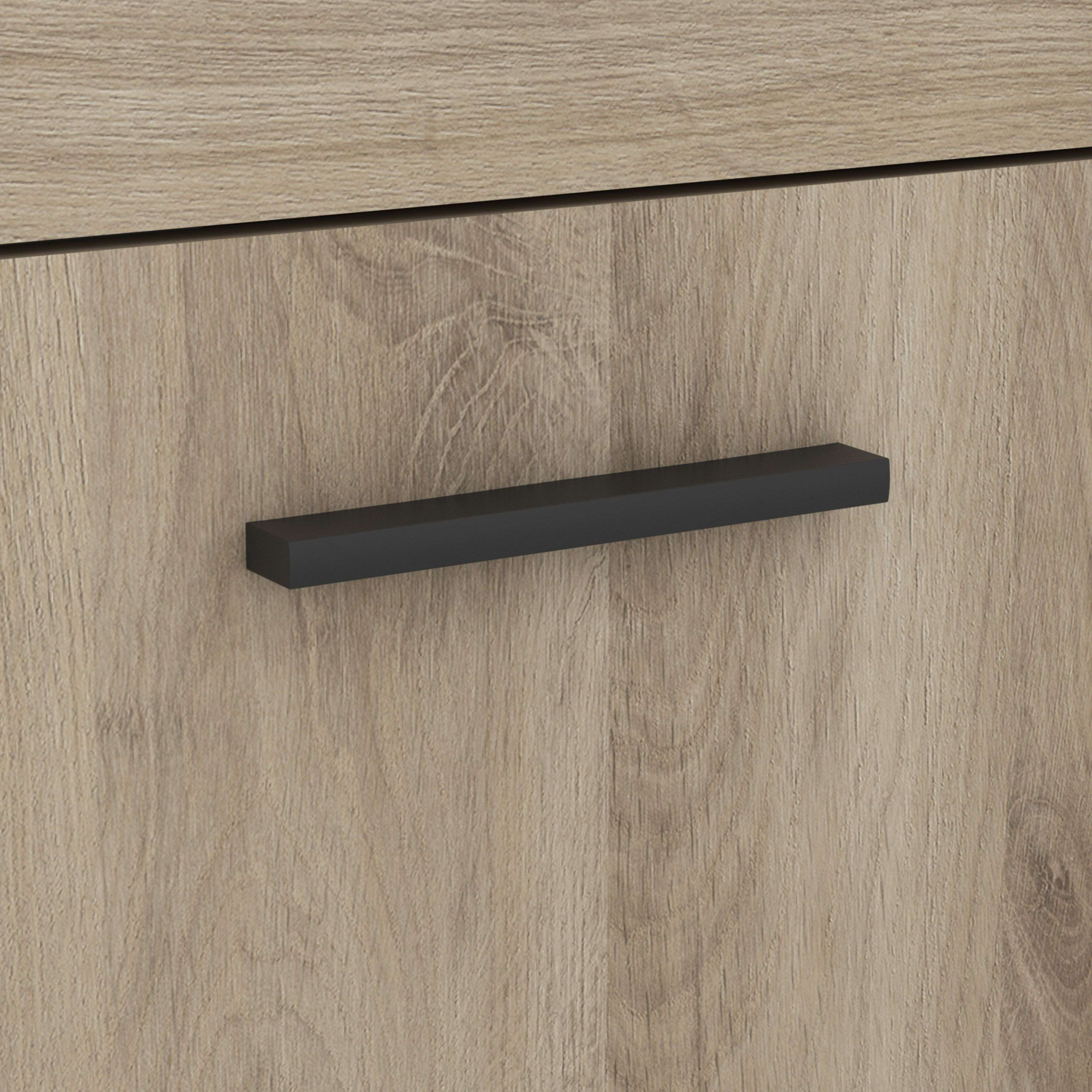 Un tirador negro sobre una superficie de madera marrón claro con veta.
