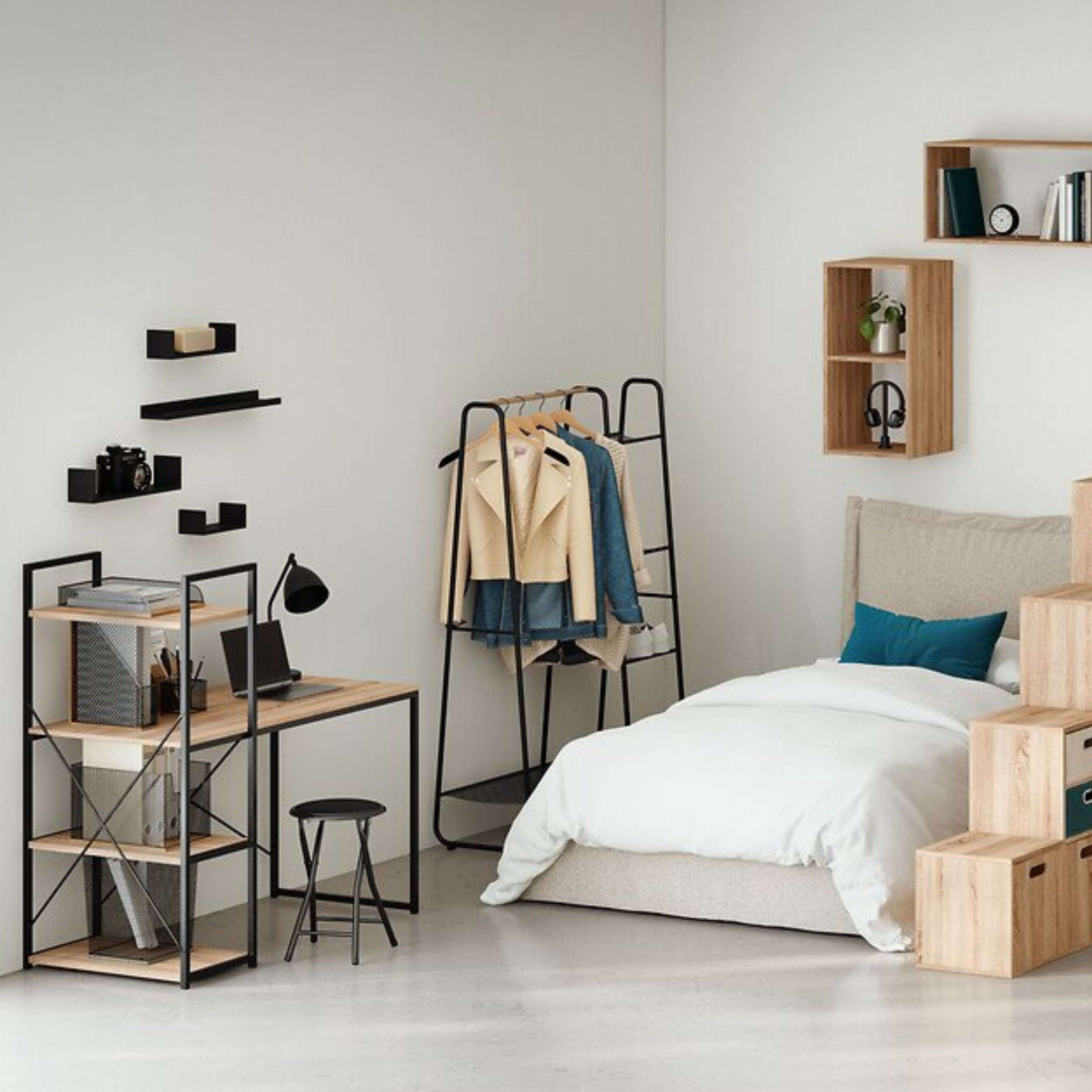 Un dormitorio con cama, escritorio, perchero y estantes.