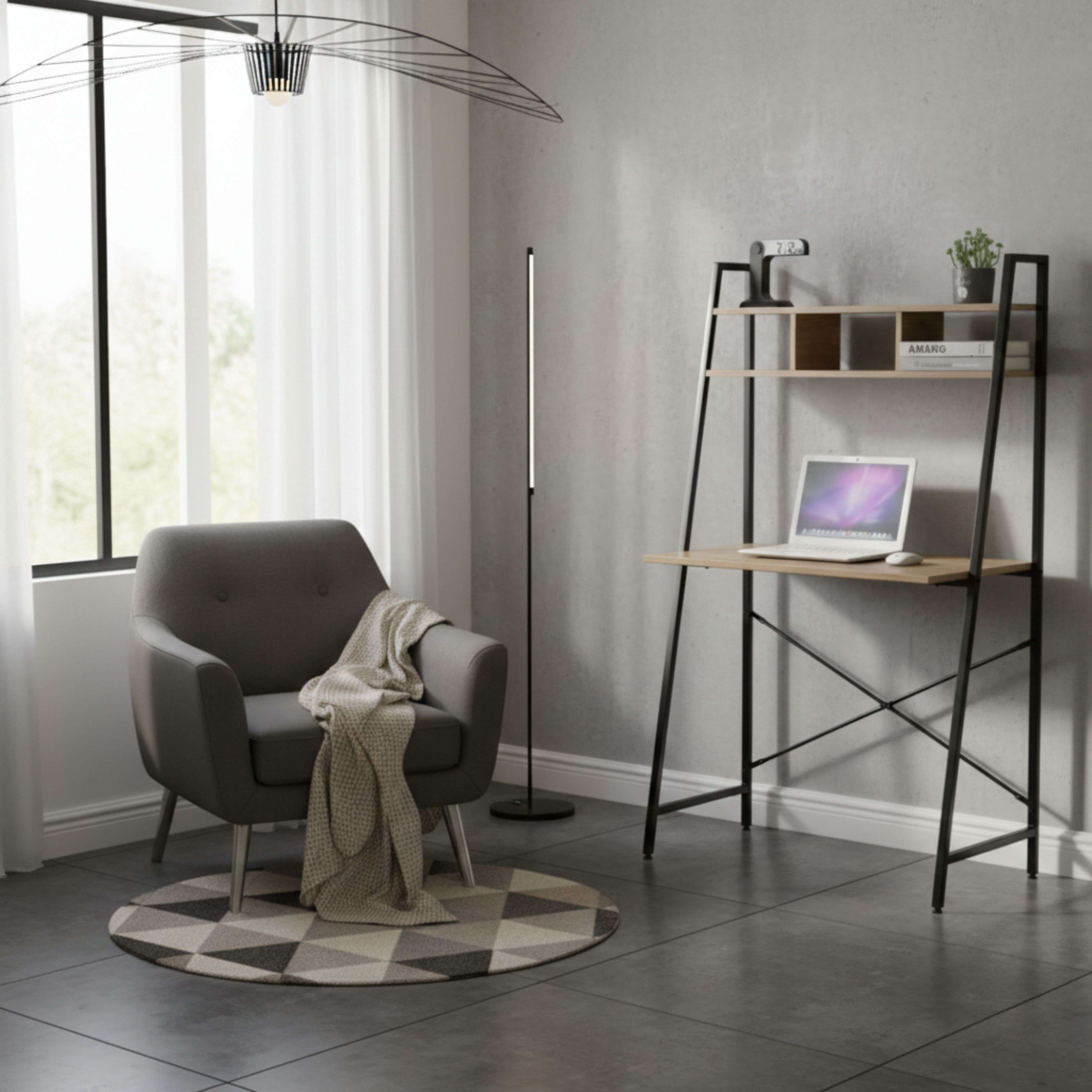 Un sillón gris con manta junto a ventana. A la derecha, un escritorio con portátil.