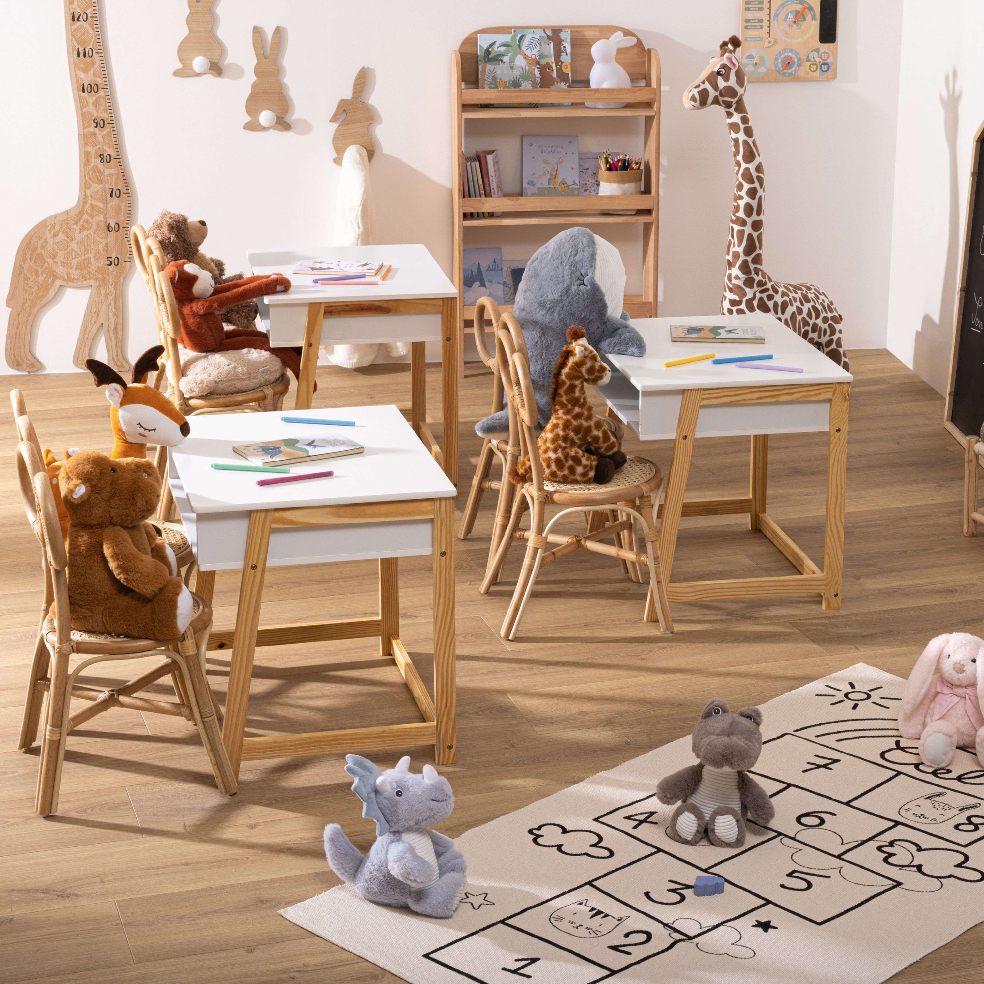 Habitación infantil con animales de peluche en escritorios y alfombra de juegos.