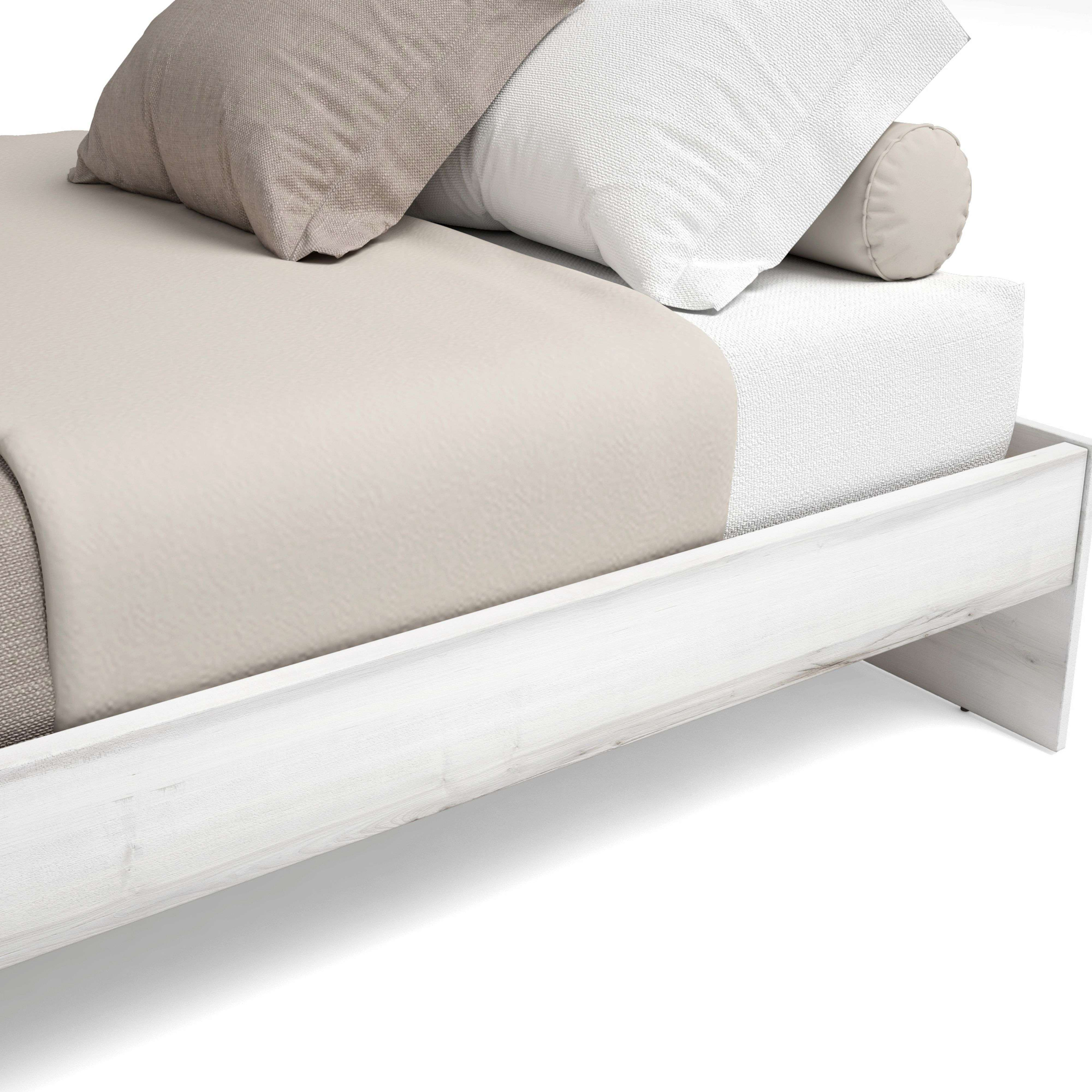 Una cama blanca con almohadas y manta. Vista cercana.