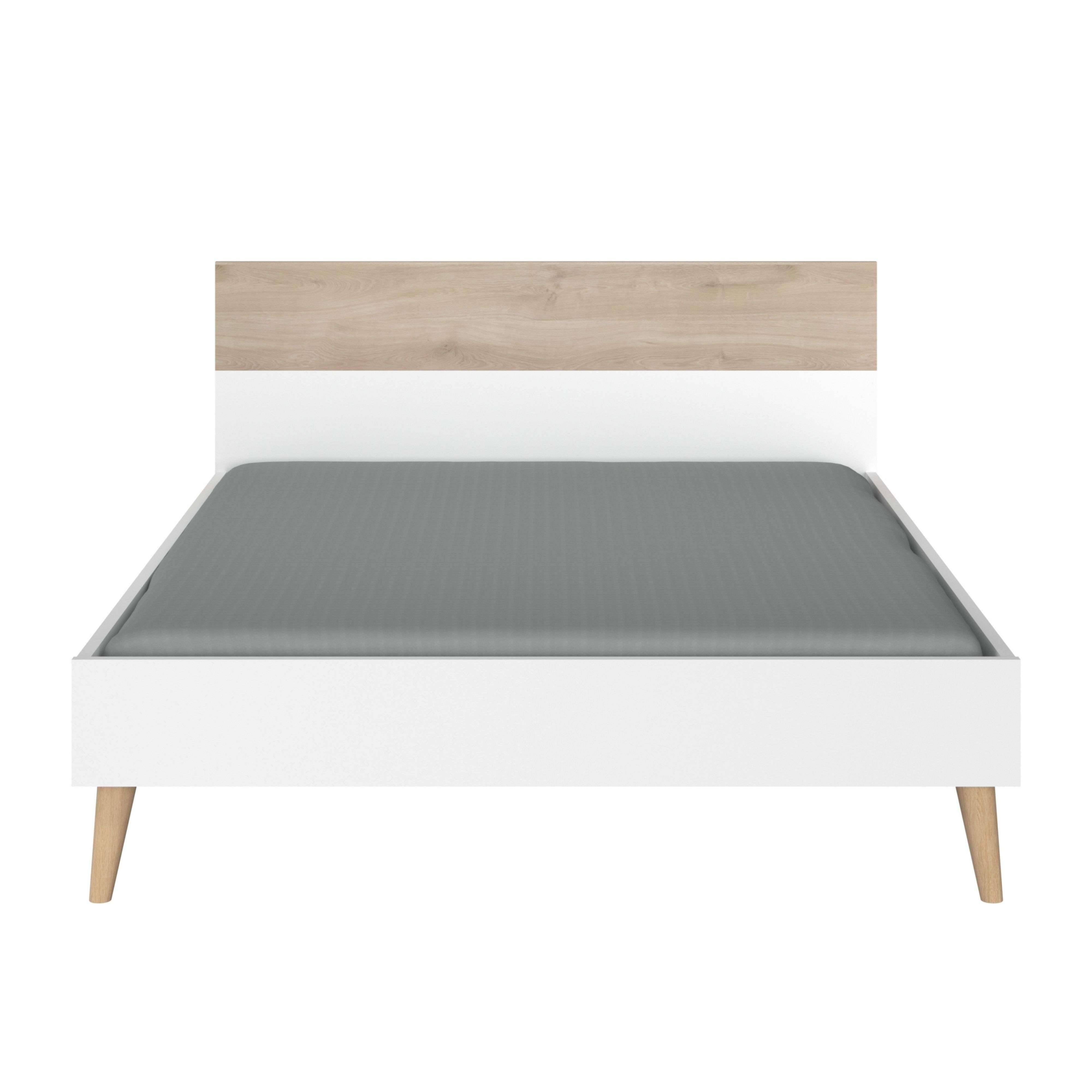 Una cama blanca con cabecero de madera y colchón gris.