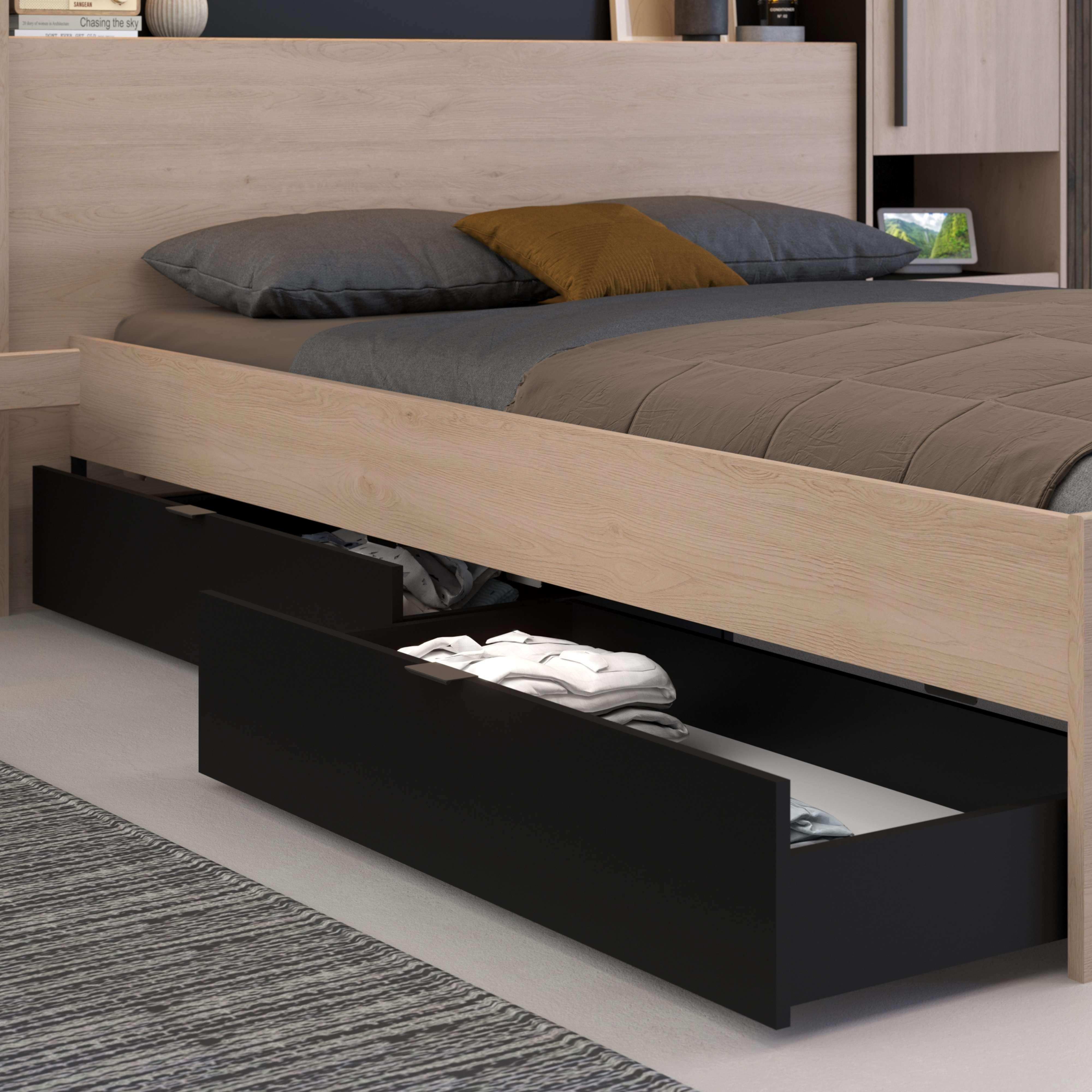 Cama de madera con cajones abiertos y ropa, ropa de cama gris y marrón.