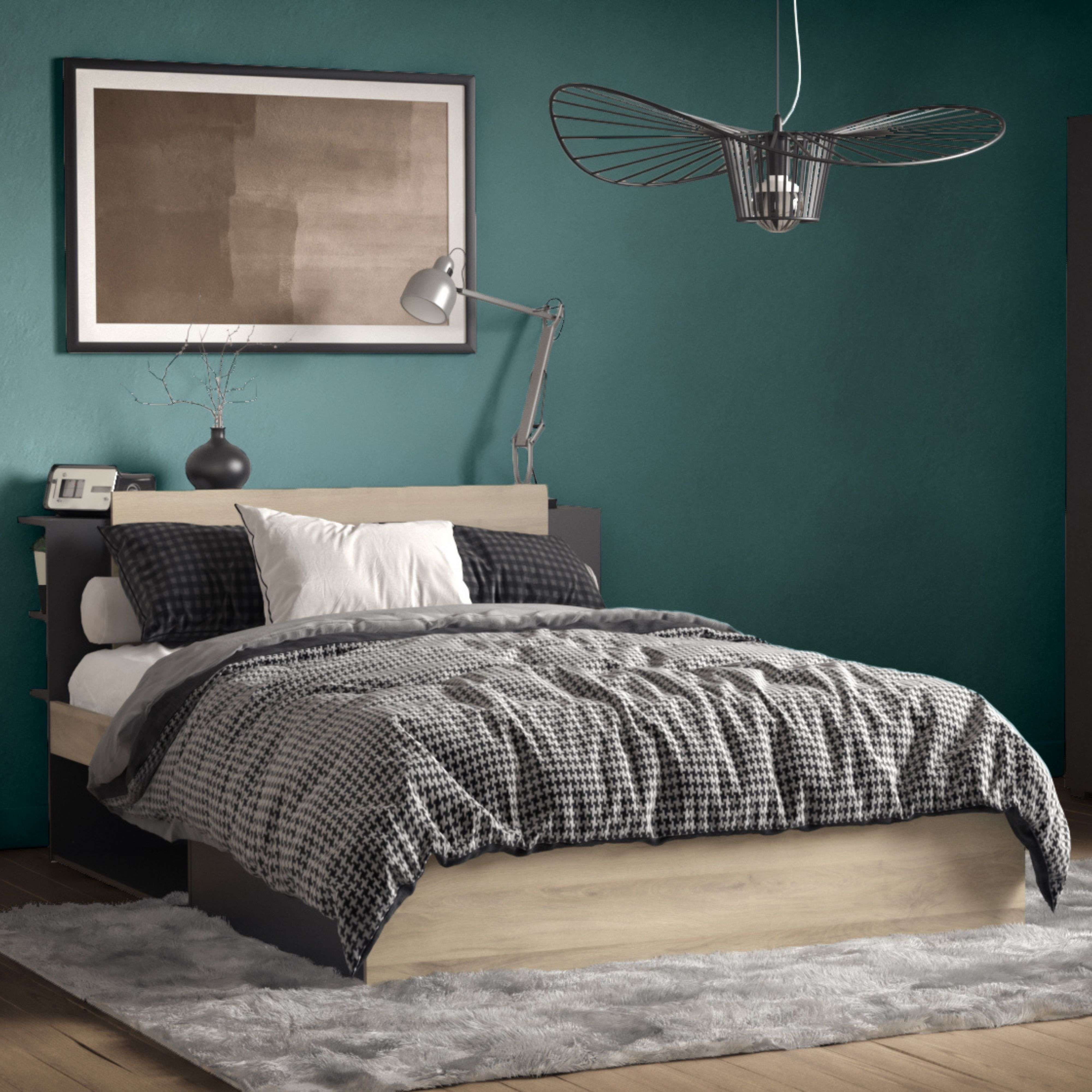 Un dormitorio moderno con cama de madera, edredón estampado y cuadro en la pared.