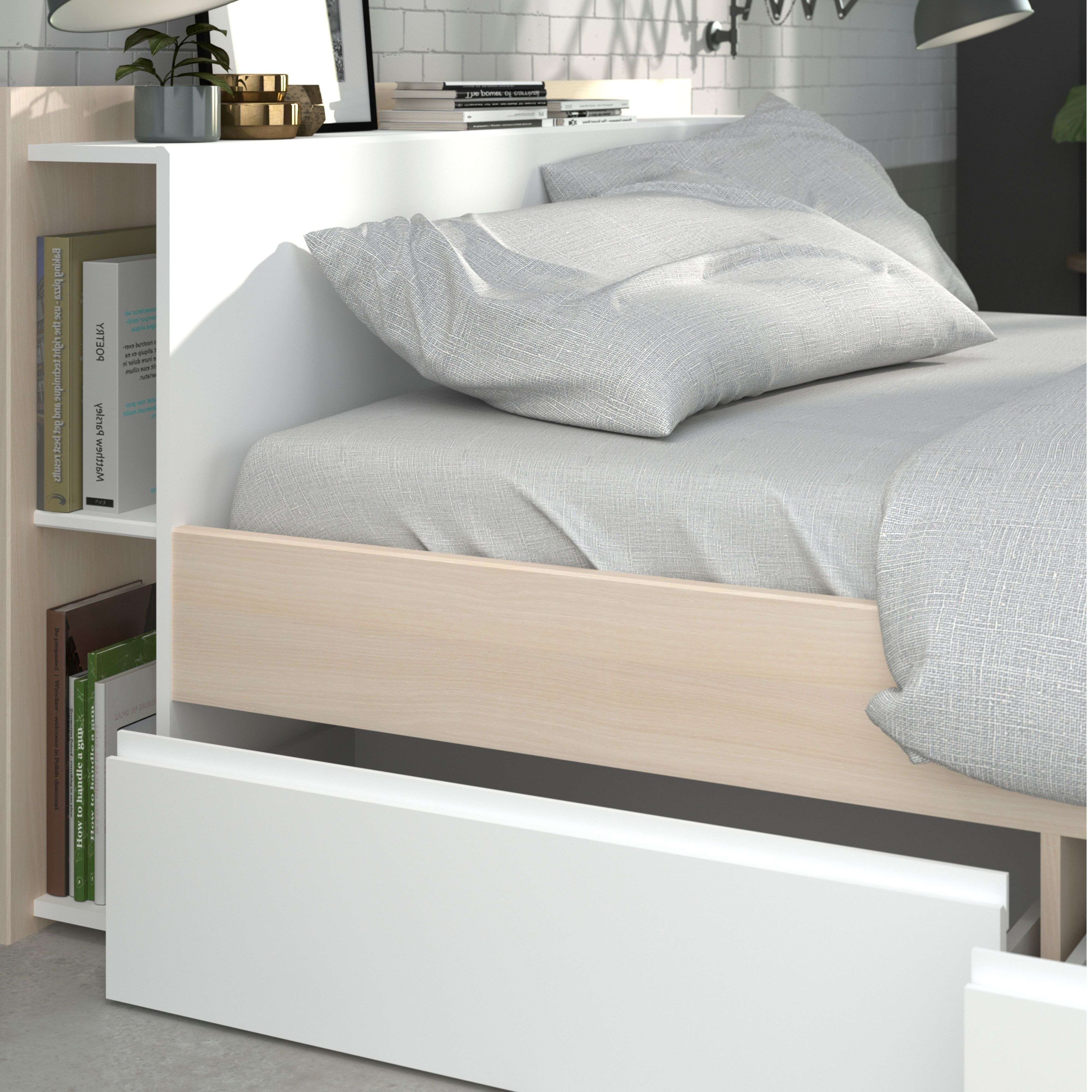 Una cama con detalles de madera clara, cajones blancos y ropa de cama gris.