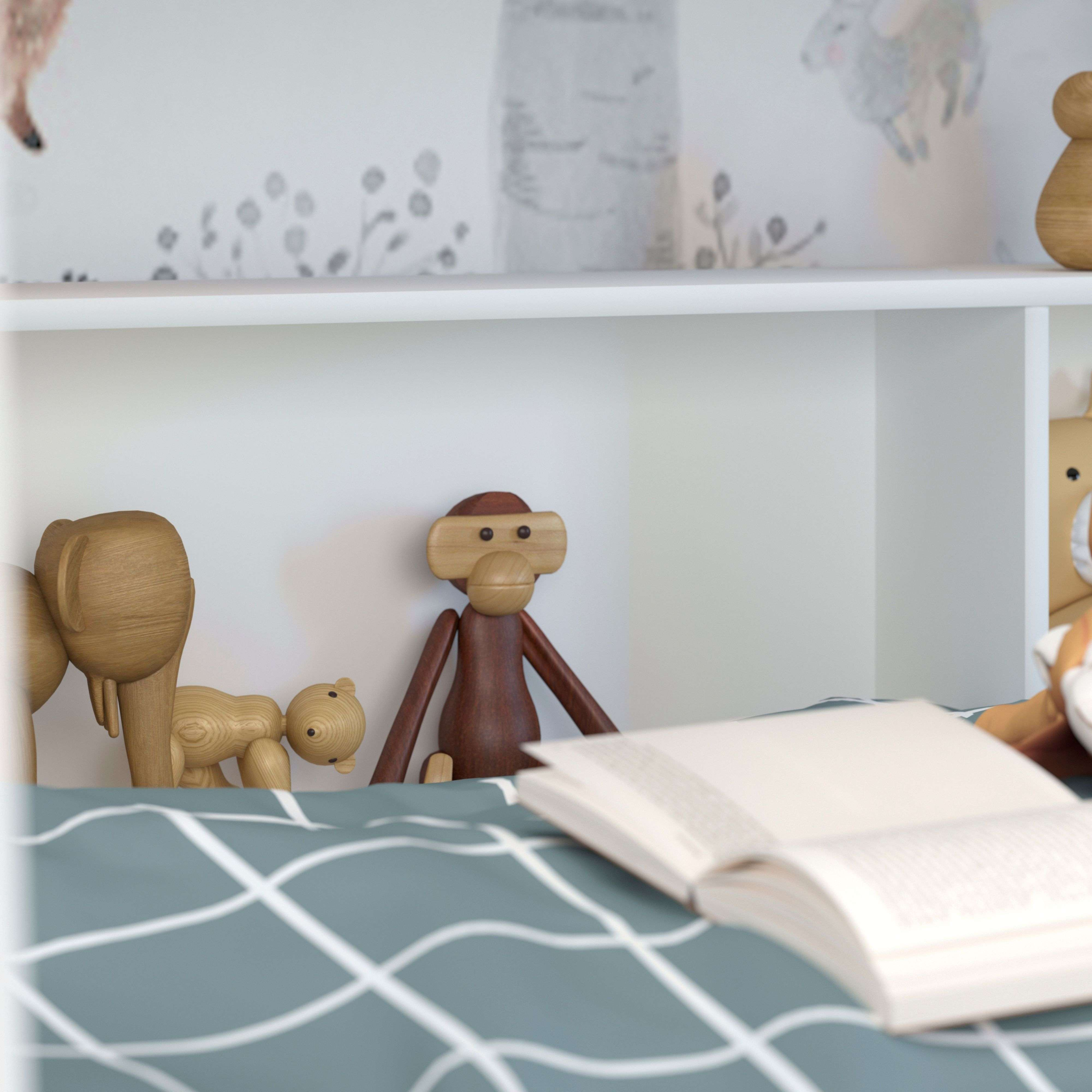 Juguetes de elefante, mono y oso de madera en una cama a cuadros azul y blanca.