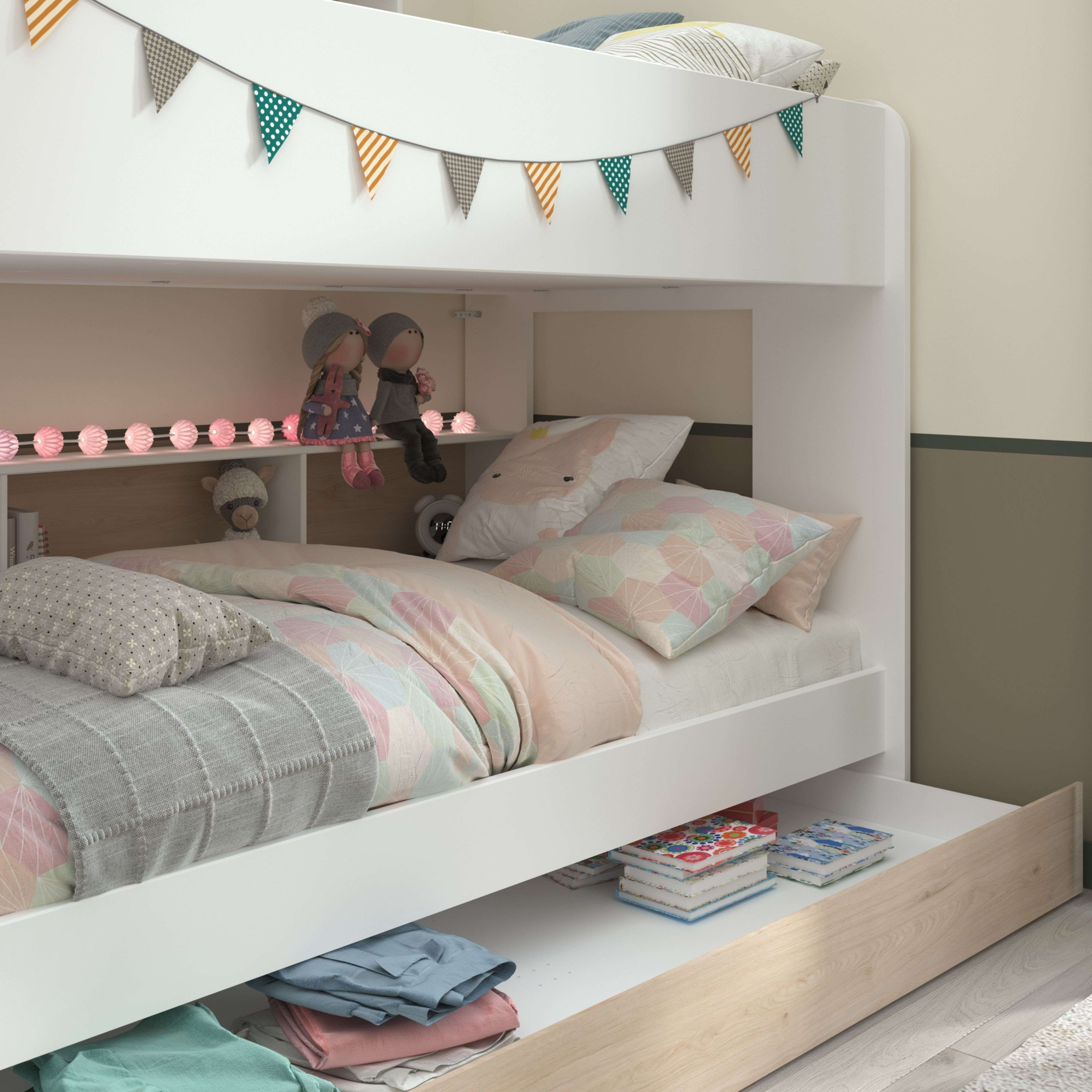 Una litera blanca decorada con guirnaldas y juguetes. Debajo hay ropa y libros.