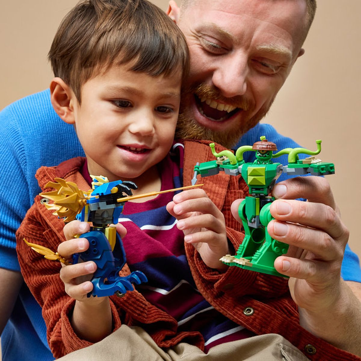 Hombre y niño juegan con figuras de Lego azules y verdes.