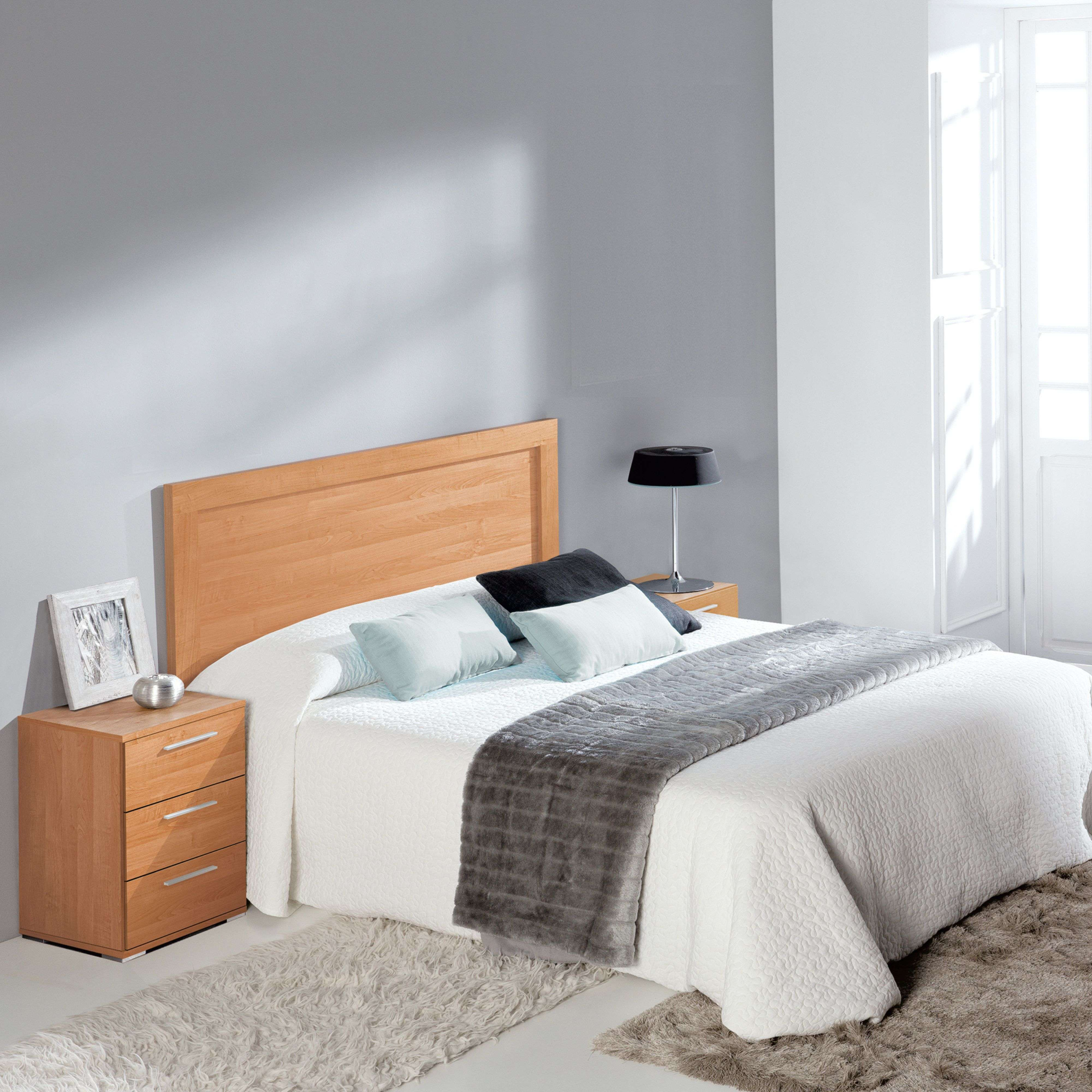 Un dormitorio con cama de madera, mesitas de noche, lámpara y alfombras.