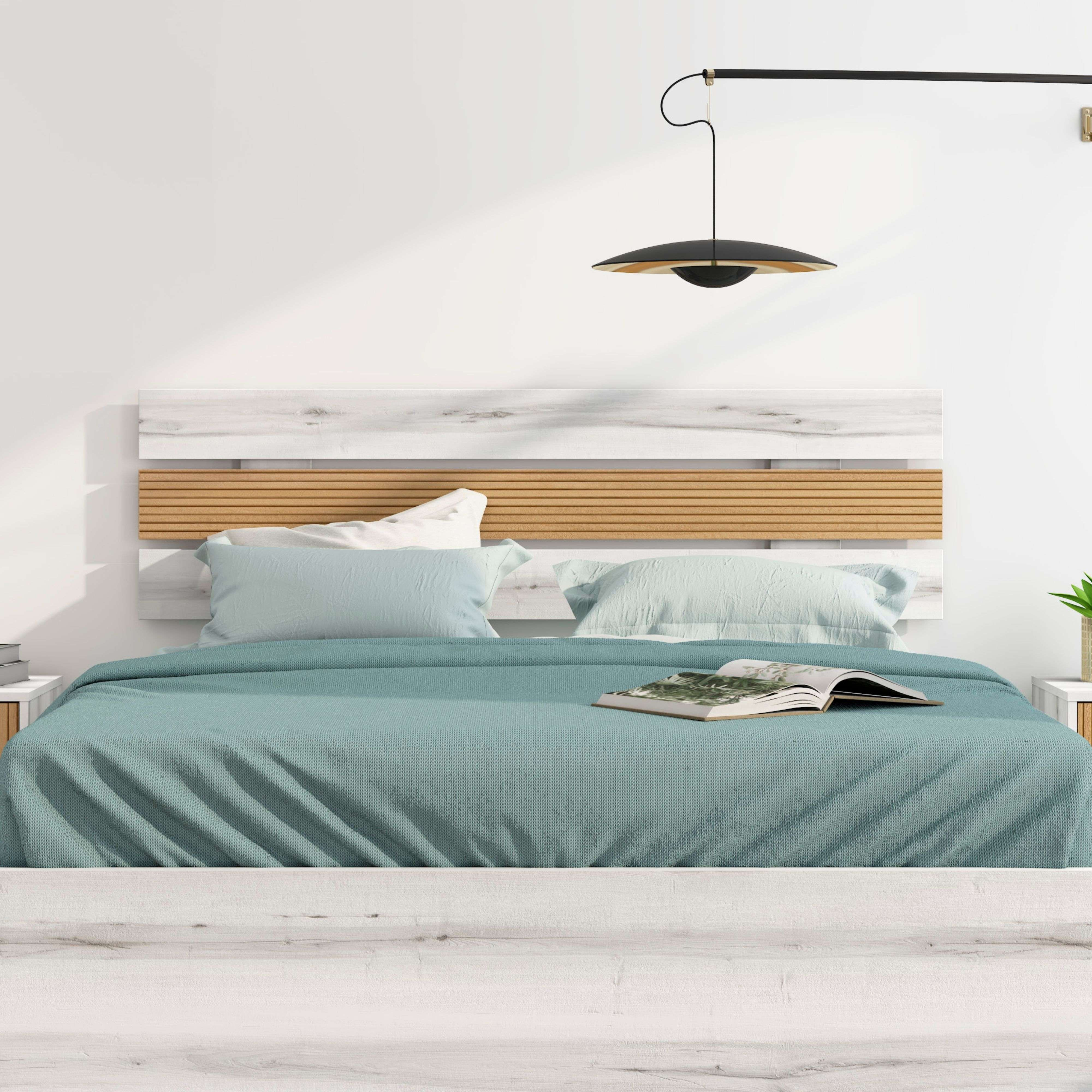 Una cama con un cubrecama verde azulado, almohadas azul claro y un libro abierto.