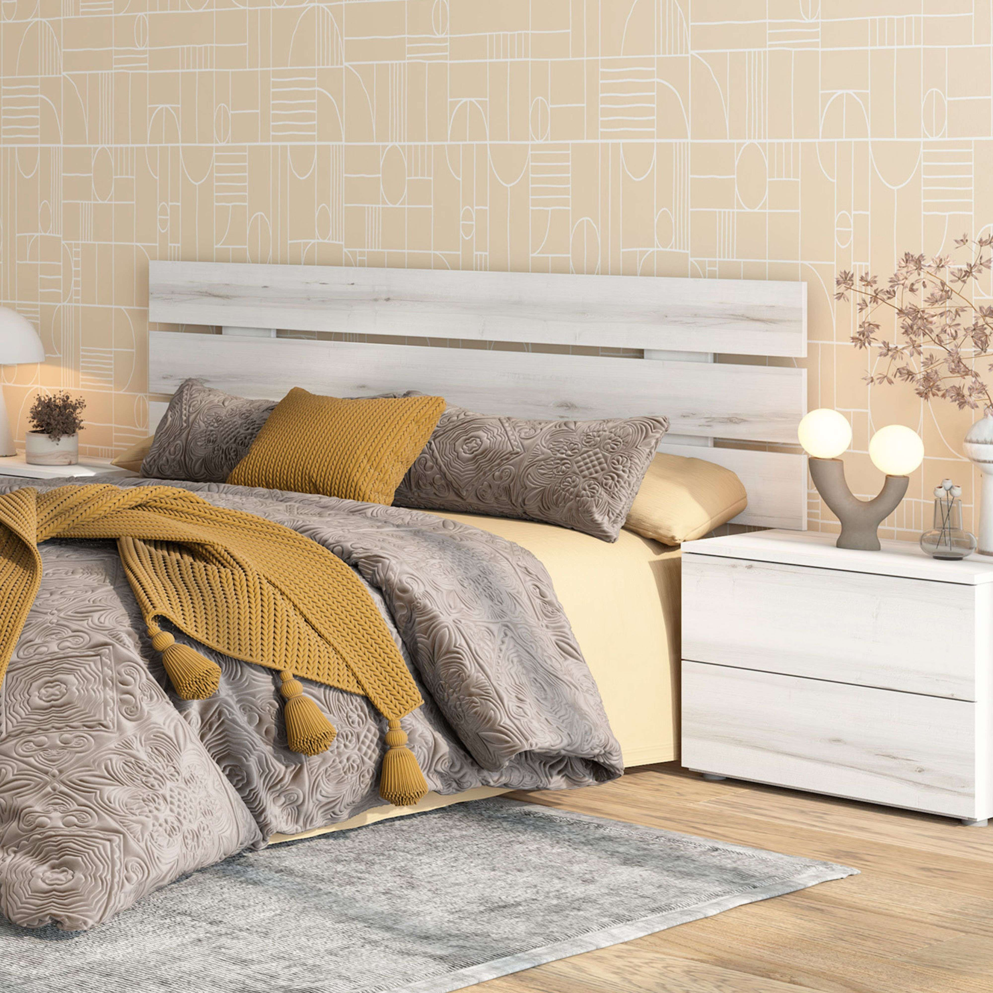 Una cama con cabecero blanco, ropa de cama gris, manta amarilla y mesita de noche.
