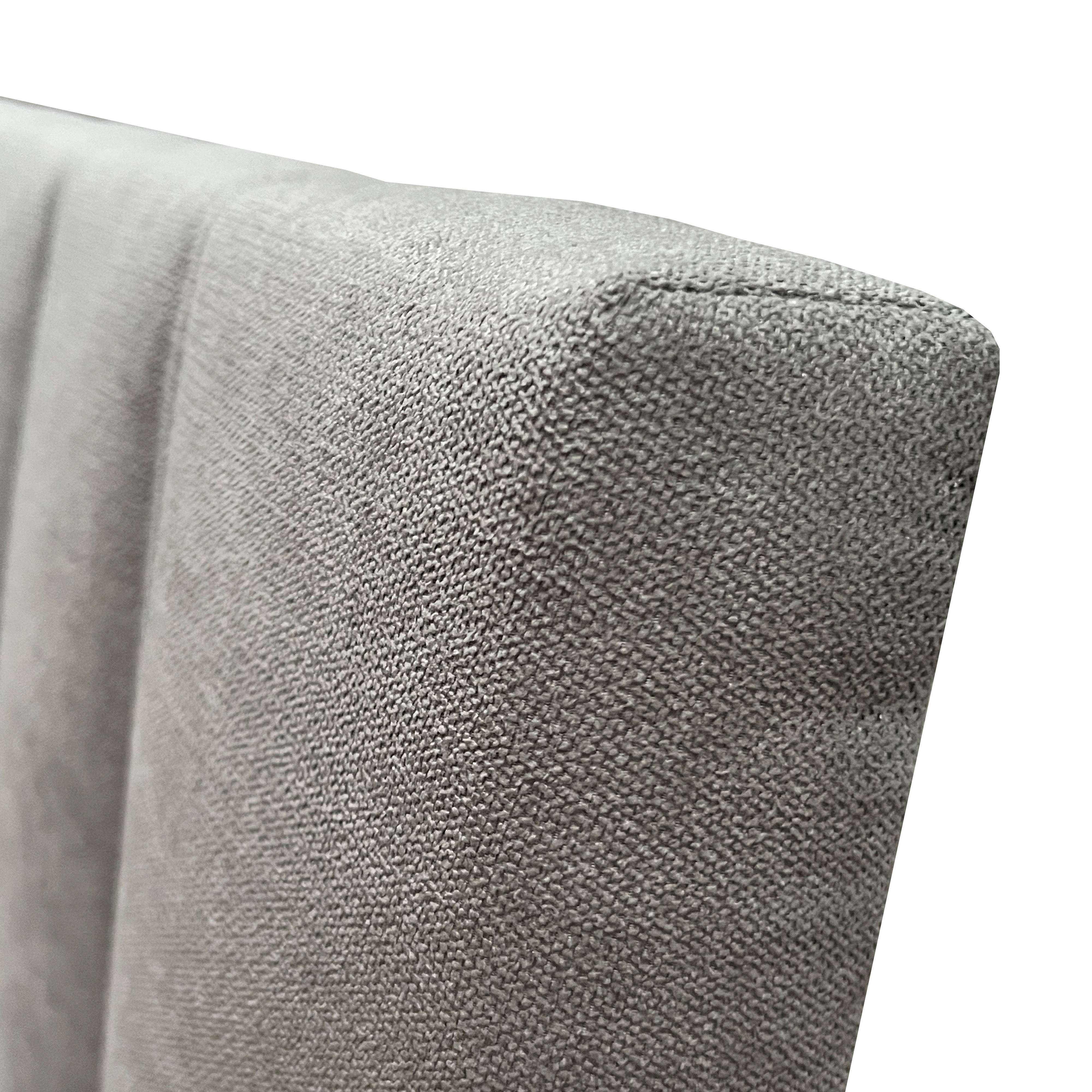 Tela gris con textura fina, primer plano de la esquina de un mueble tapizado.
