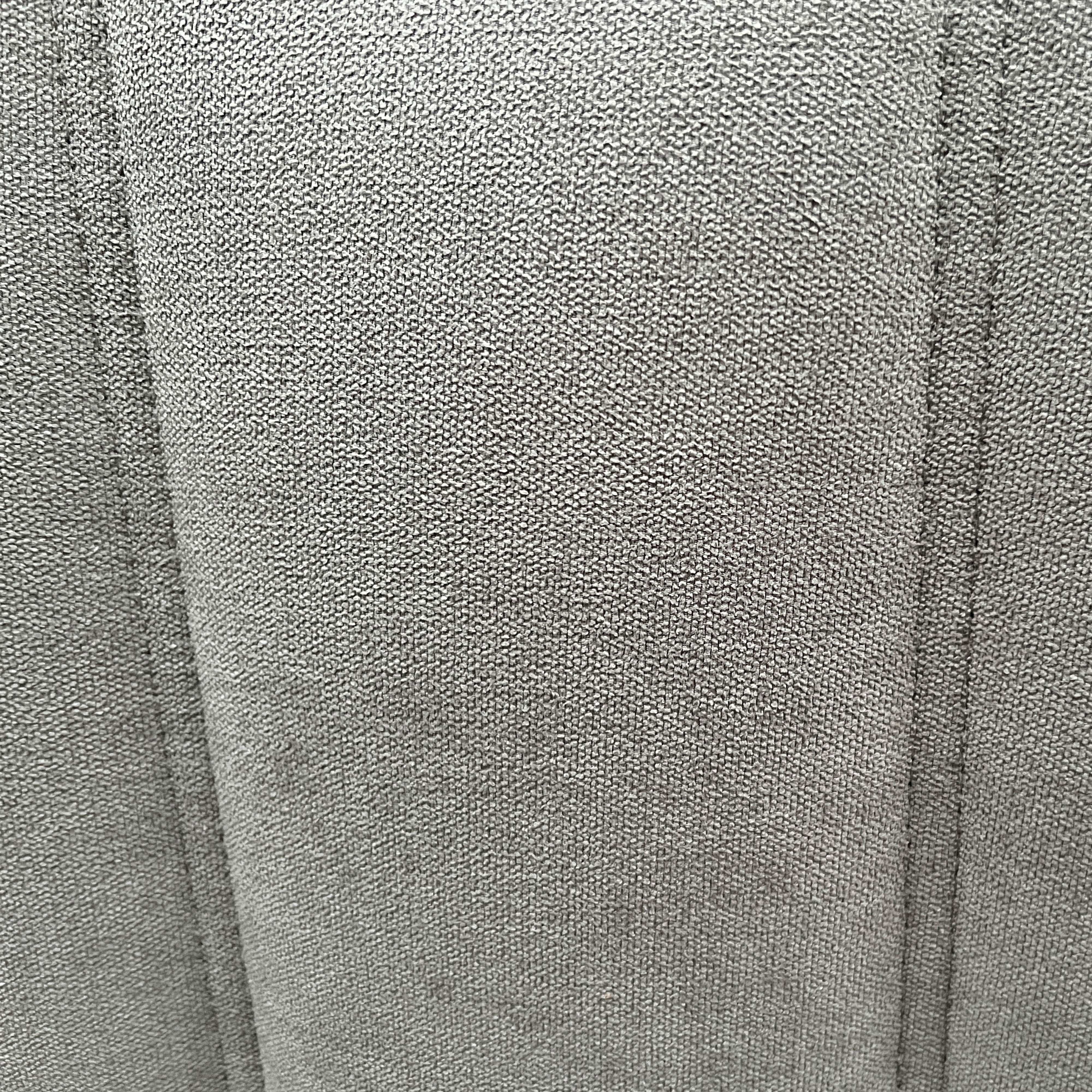 Tela gris con pliegues verticales y textura gruesa.